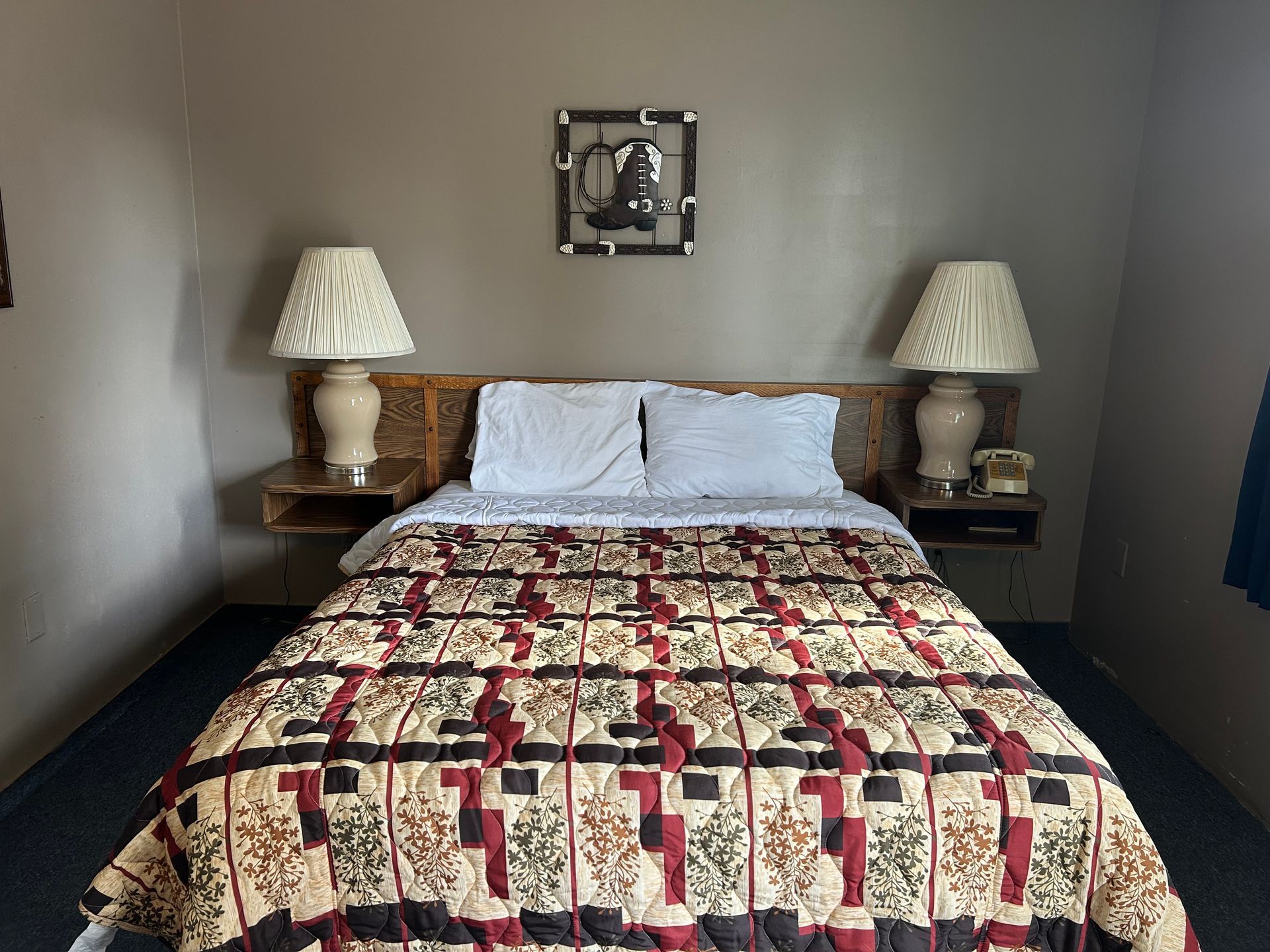 A hotel room with a bed , two lamps and a picture on the wall.