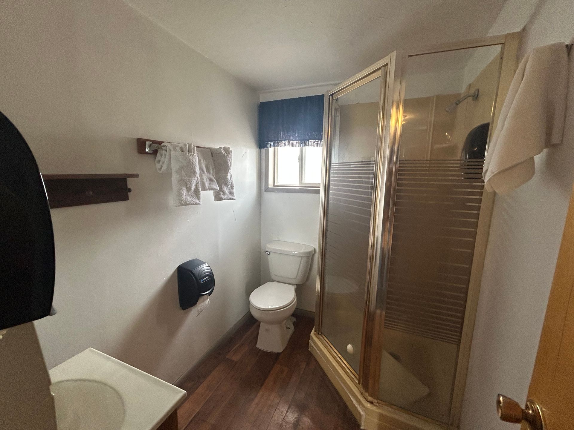 A bathroom with a toilet , sink , shower and window.