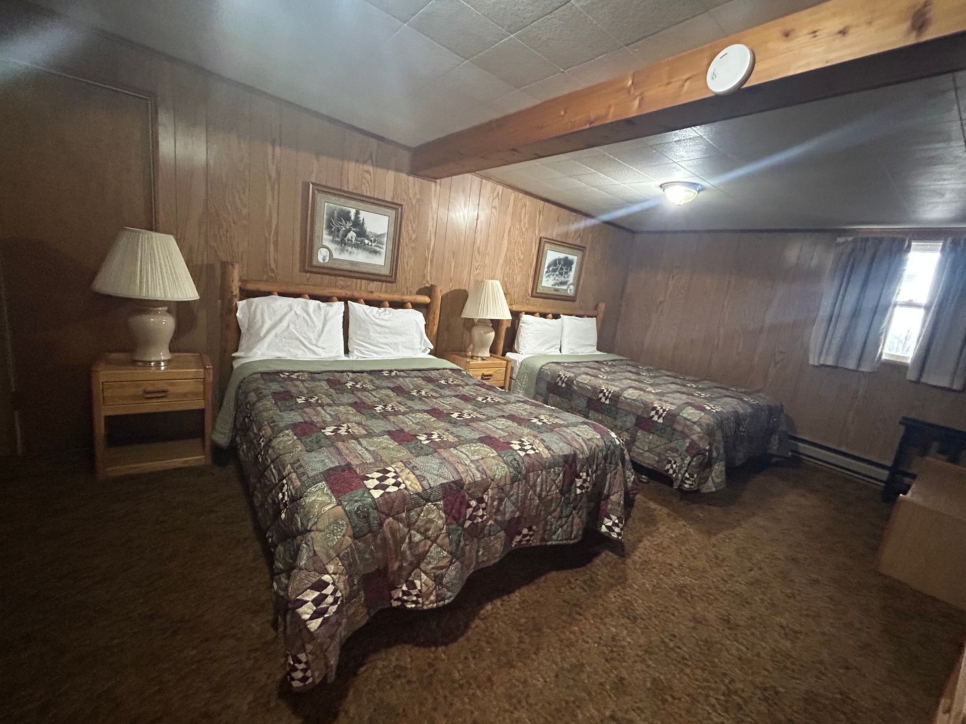 A hotel room with two beds and two lamps.
