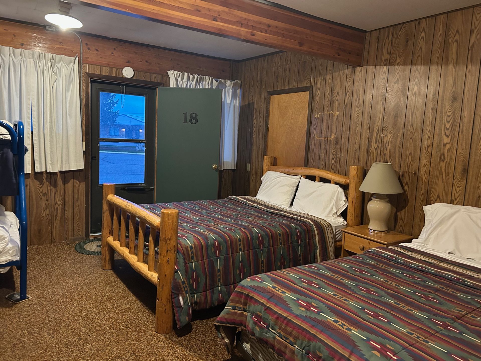 Cabin interior with two beds, a bunk bed, door marked 
