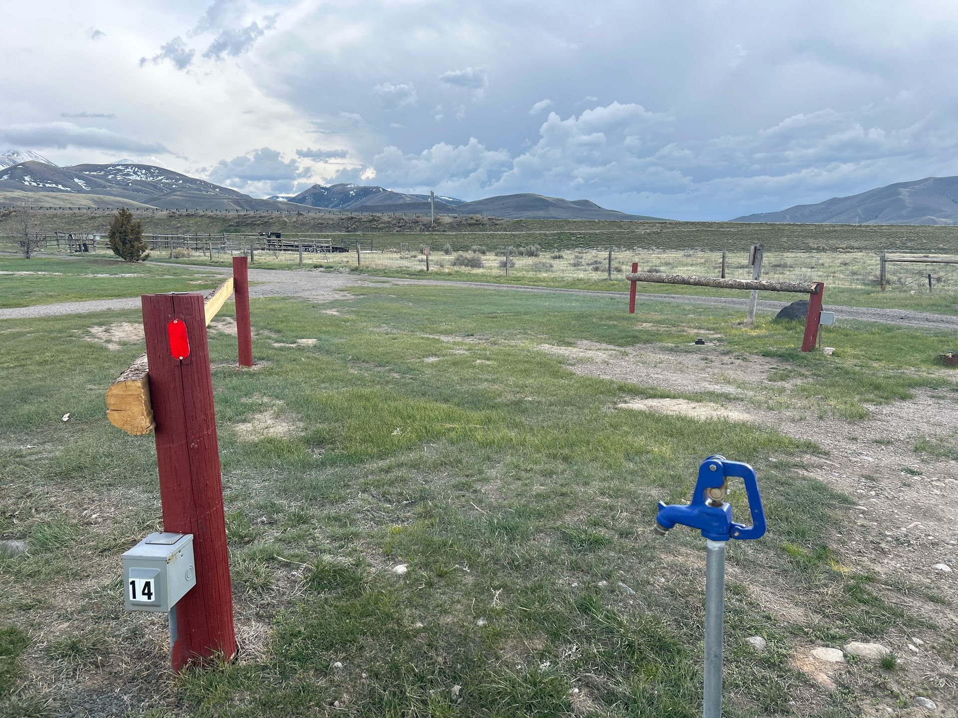 A red pole with a red light on it is in the middle of a grassy field.