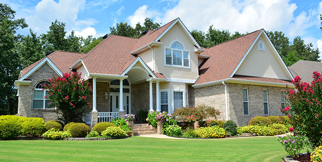 A large house with a red roof and a large lawn in front of it.