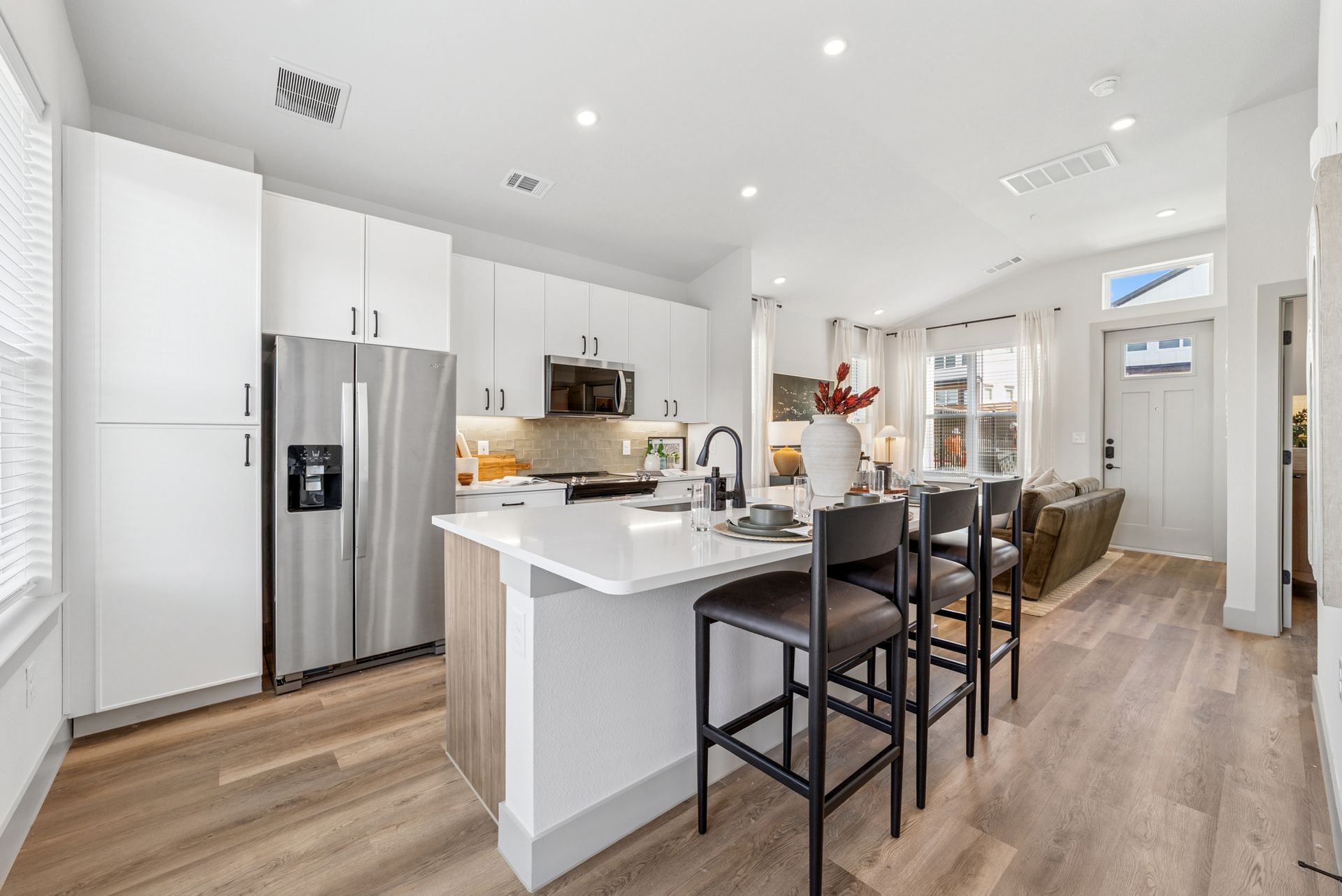 Modern kitchen with white cabinets, stainless steel appliances, and a breakfast bar.