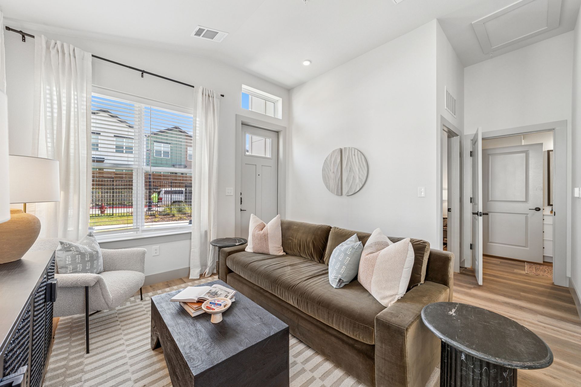 Living room with a brown couch, window, door, and a decorative wall piece.
