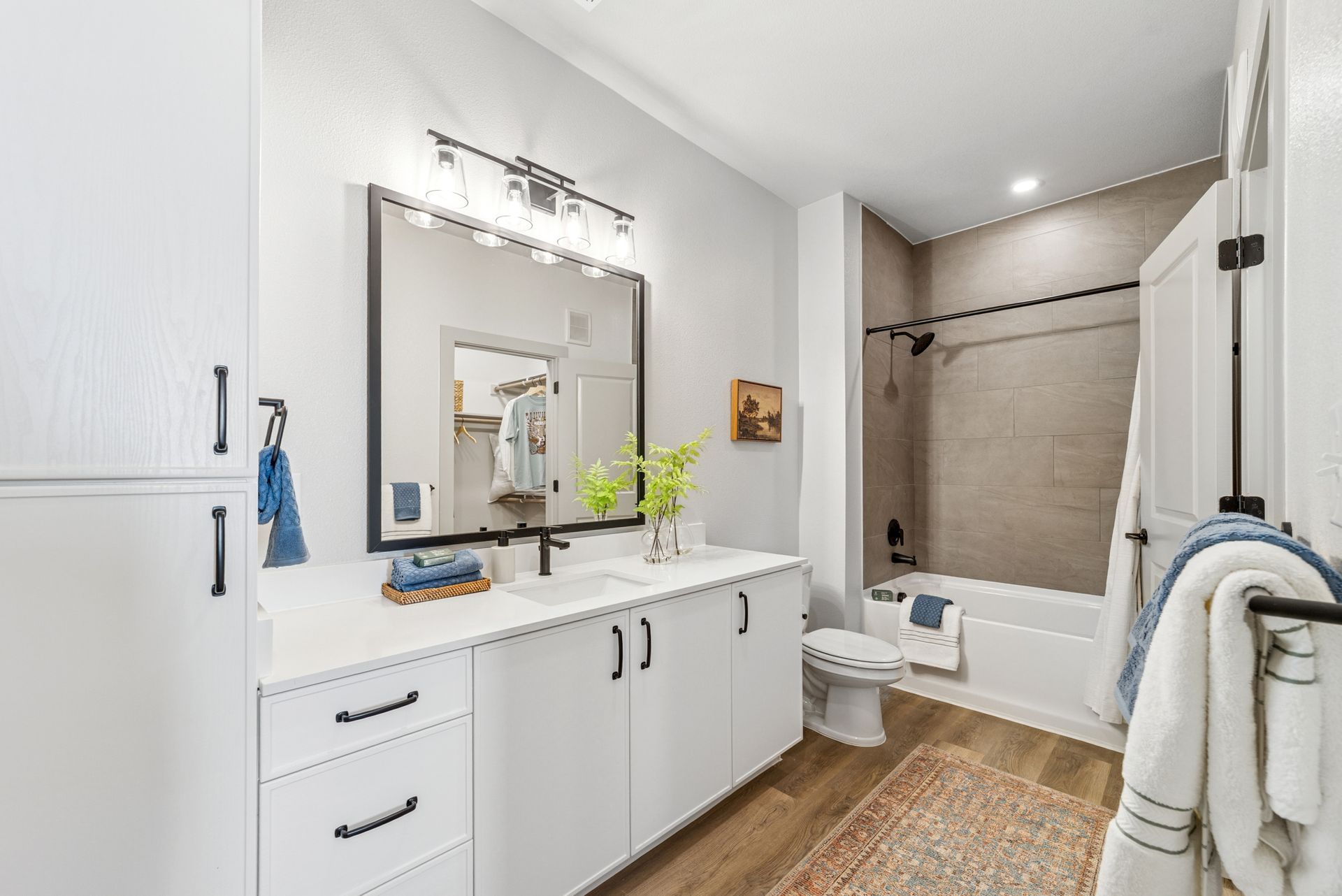 White bathroom with a vanity, mirror, tub, and toilet.