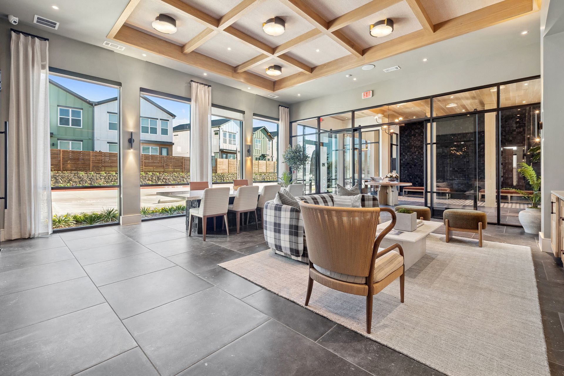 Spacious lounge with large windows, dining area, and seating. Wooden ceiling beams, neutral tones.