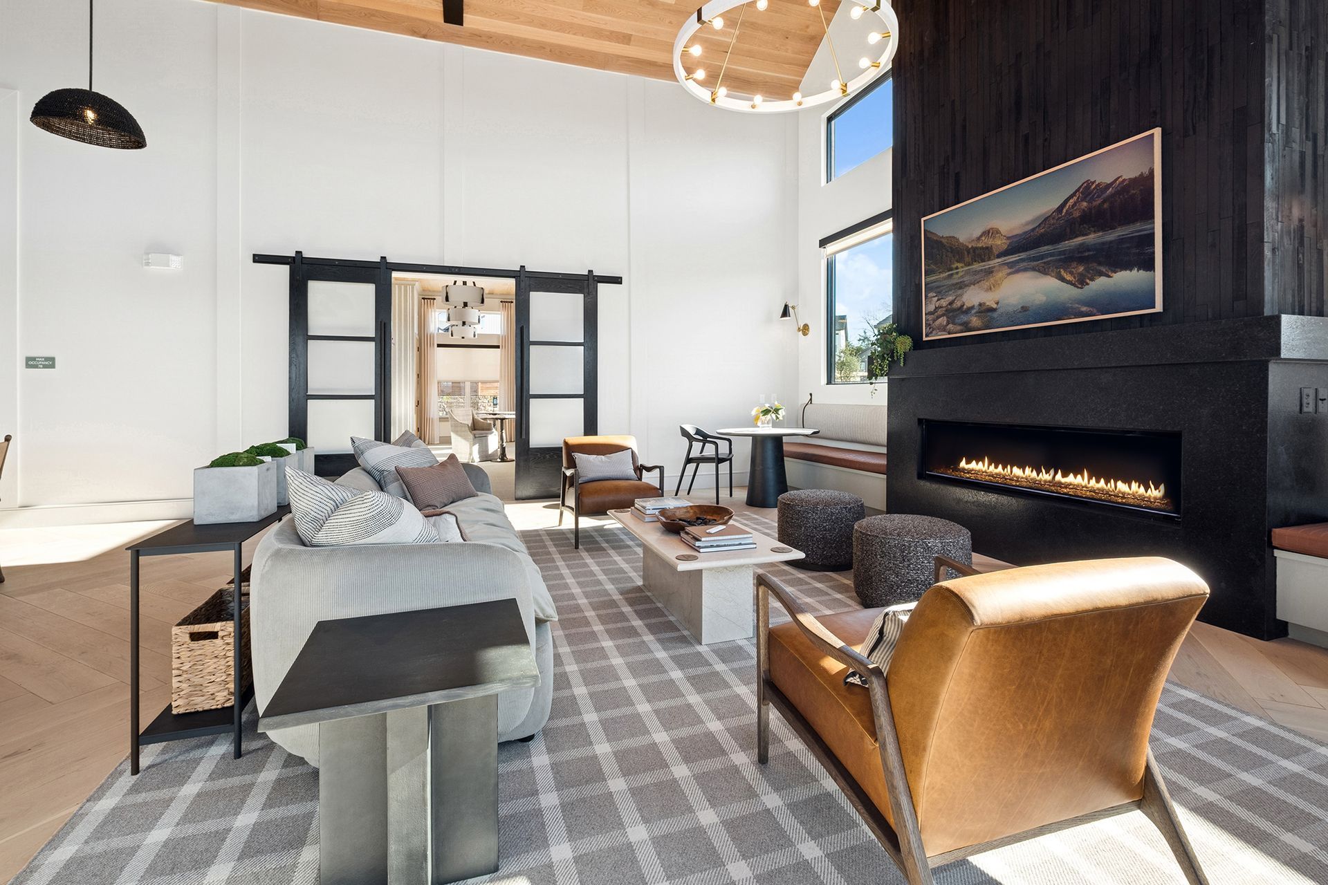 Modern living room with fireplace, TV, and sliding doors. Gray sofa, leather chairs, wood floors.