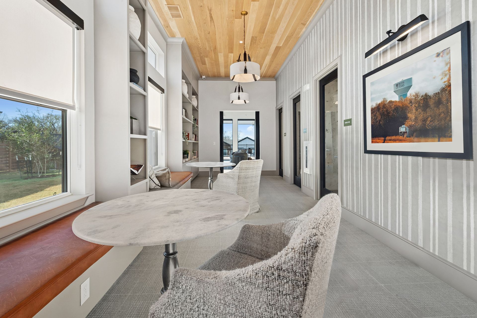 Hallway with marble table, two fuzzy chairs, built-in shelves, wood ceiling, and artwork.