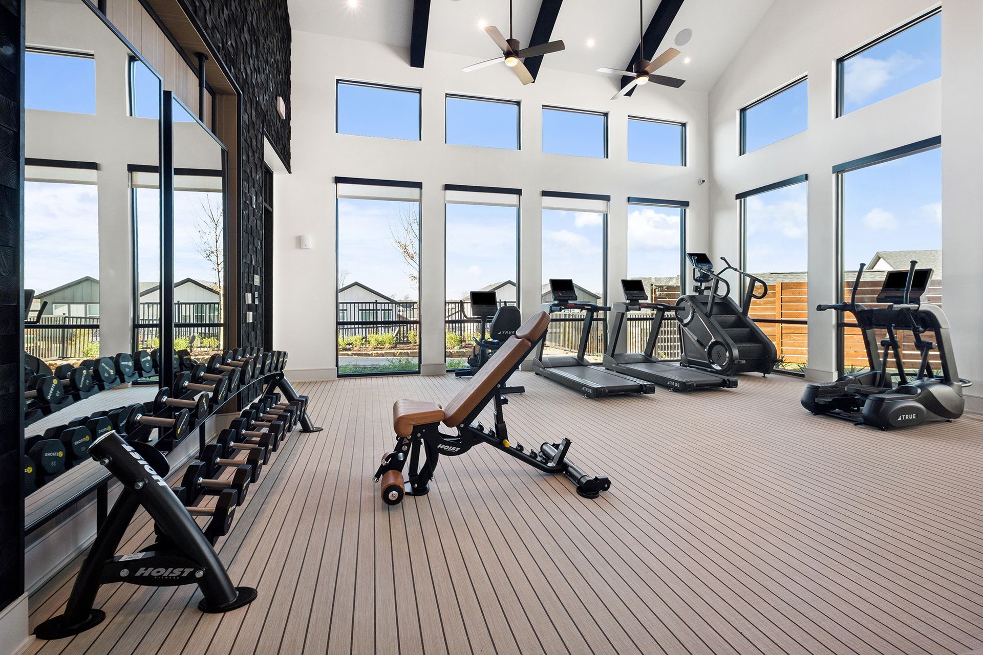 Gym with exercise equipment, large windows, and an interior view with a beige carpet.