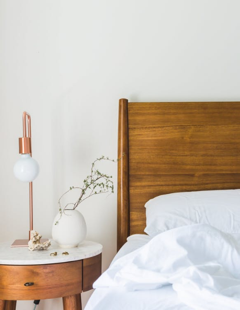 A bed with white sheets and a wooden headboard