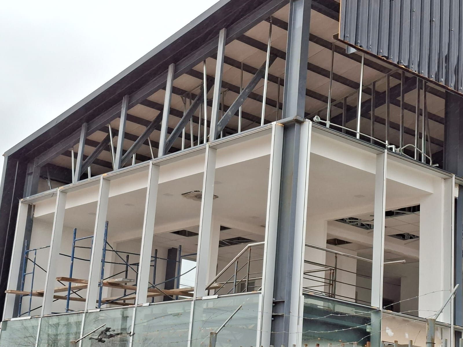 Edificio en construcción, estructura de acero gris, columnas blancas, segunda planta abierta.