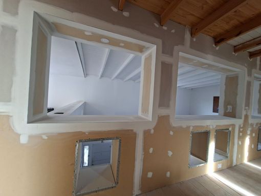 Un hombre con camisa de cuadros usa un nivel para comprobar la alineación de una pared.