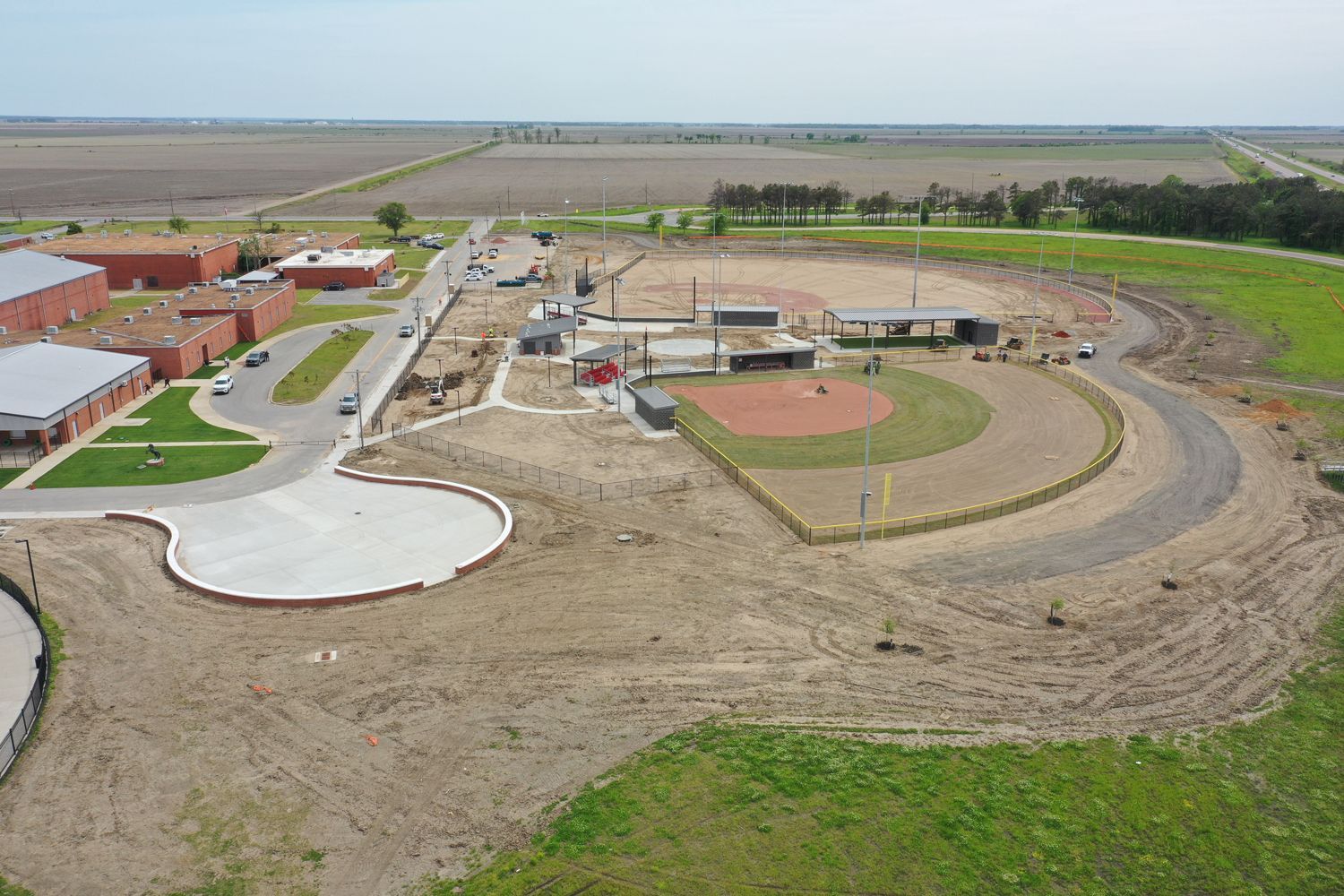 An aerial view of a baseball field with a school in the background.