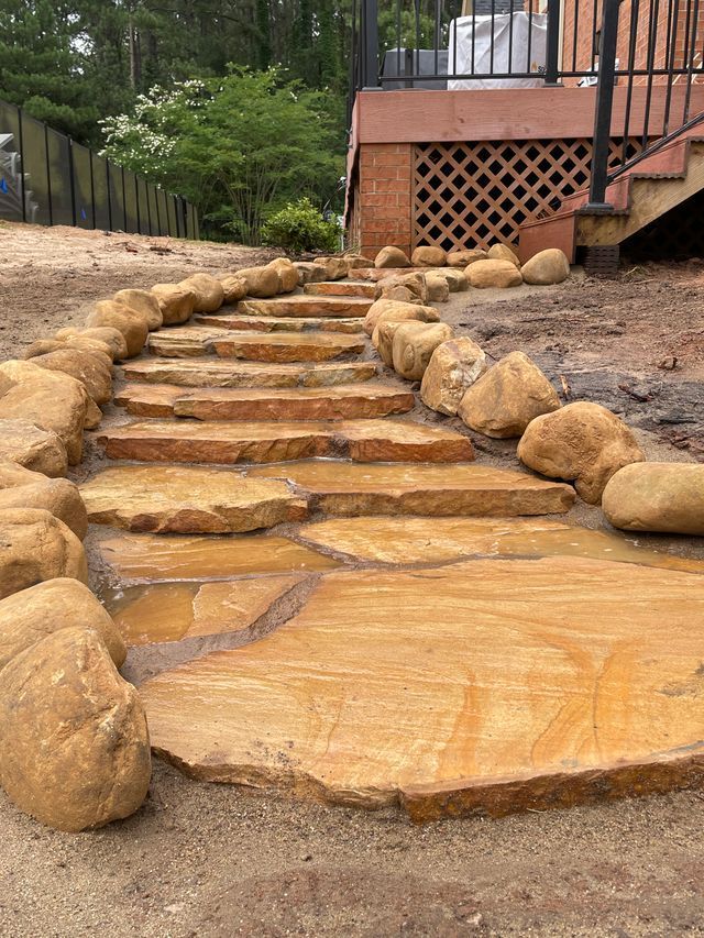 Stone steps in a sloped garden path beside a wooden deck and rocks