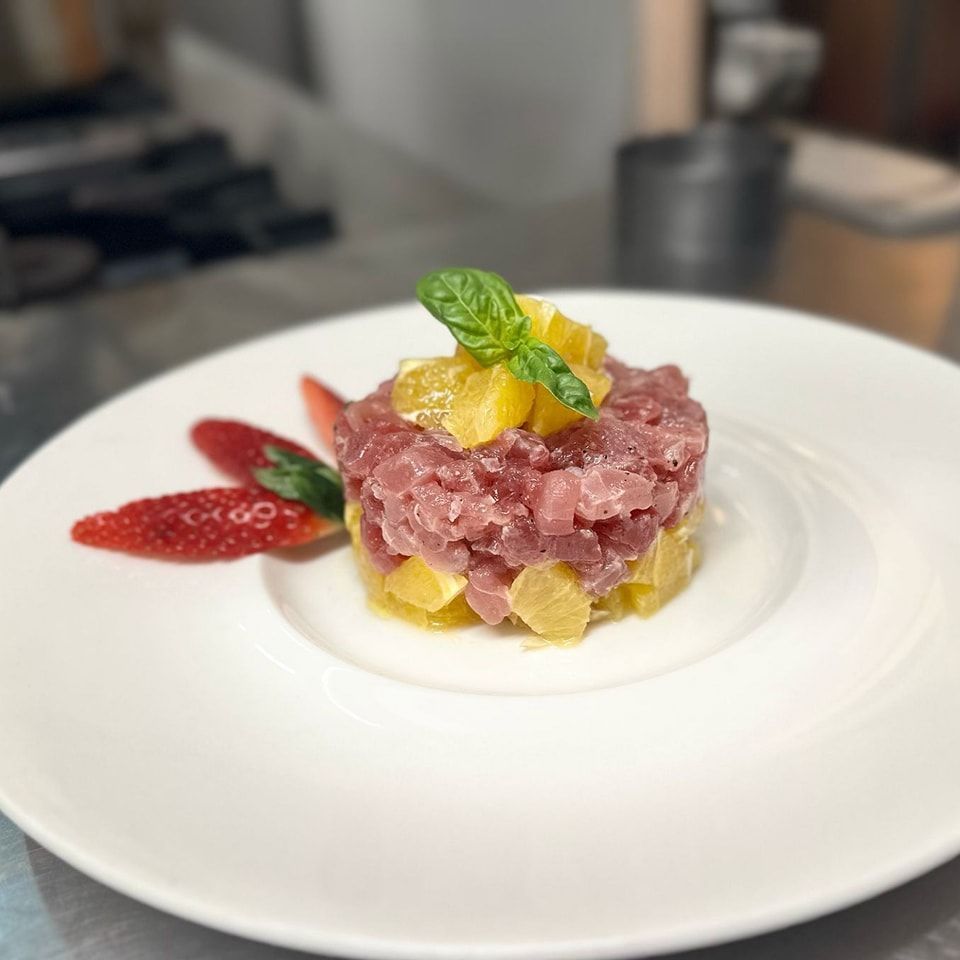 Un piatto bianco con carne, ananas e fragole
