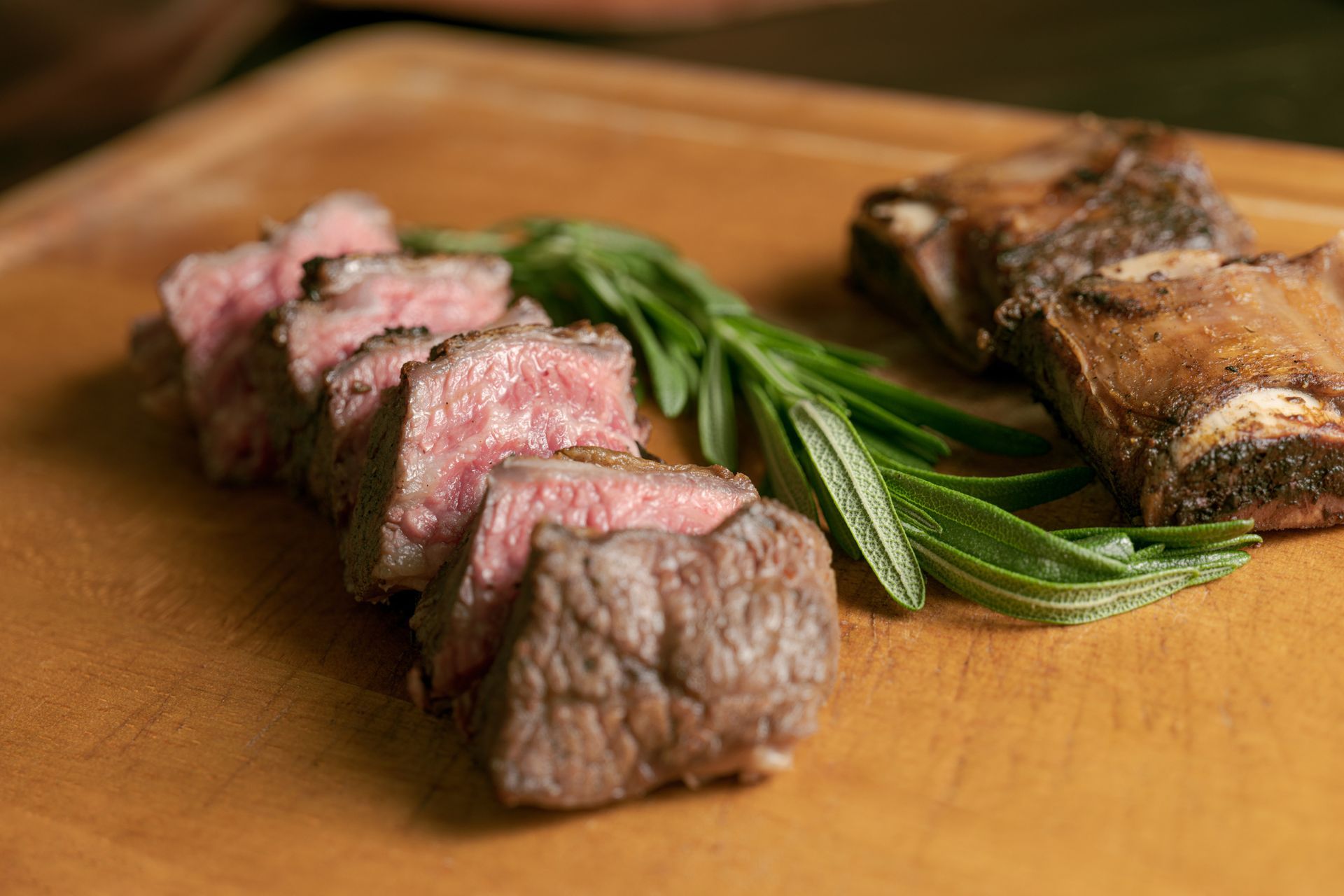 Primo piano di una bistecca e delle costolette su un tagliere.