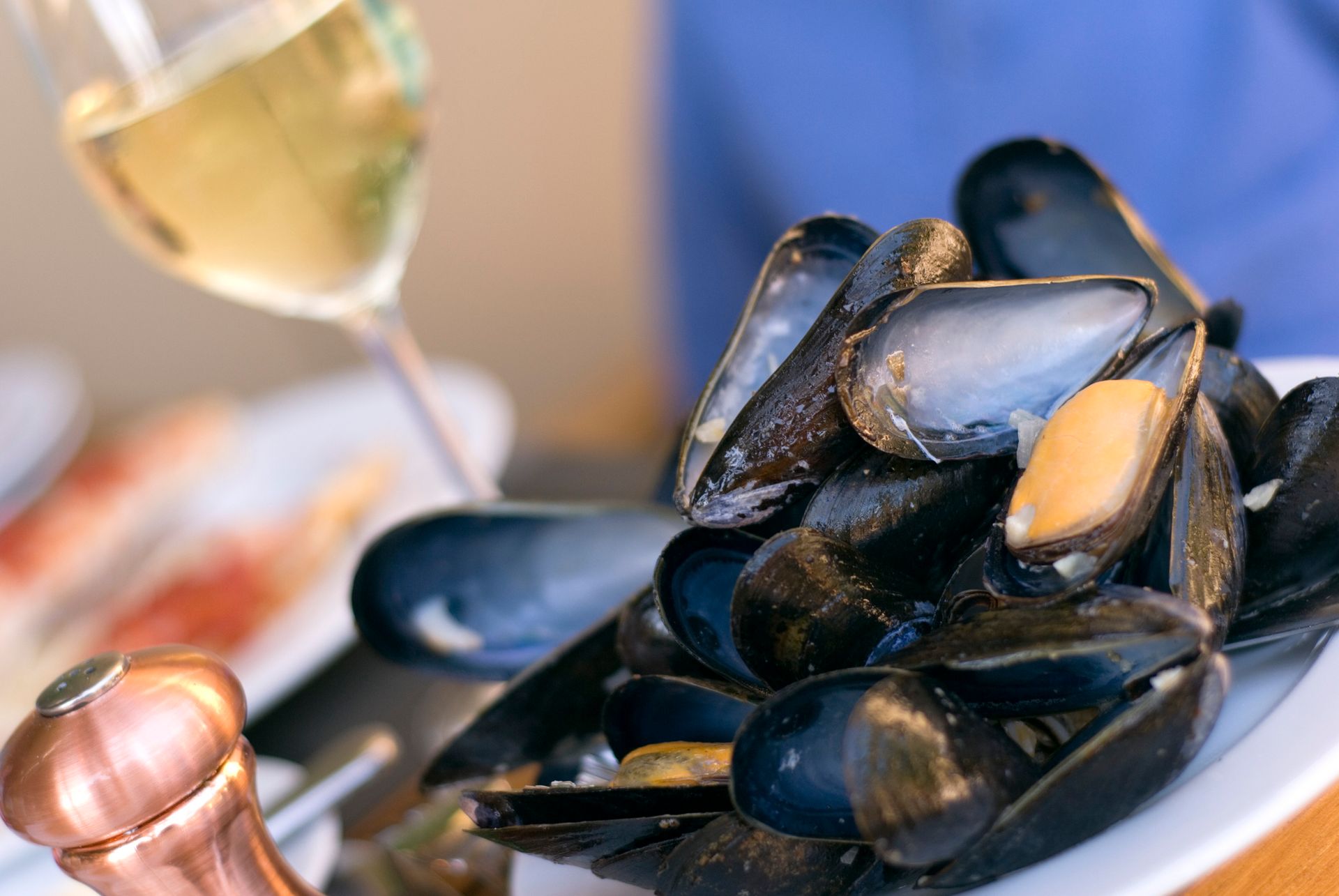 Un piatto di cozze con un bicchiere di vino sullo sfondo