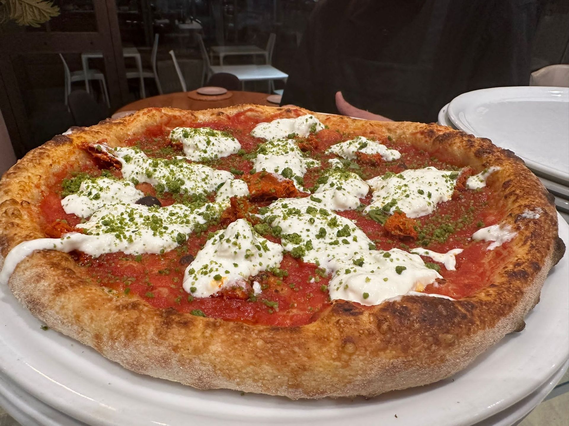 Una pizza con prosciutto e mozzarella su un piatto bianco