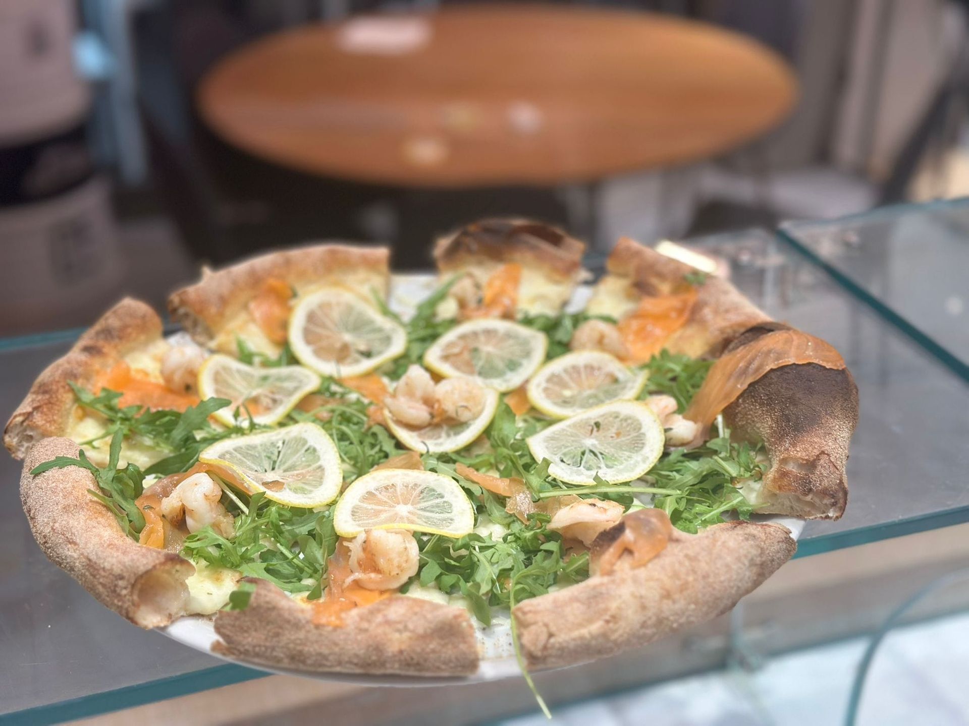 Una pizza con pancetta, formaggio e basilico su un piatto bianco.