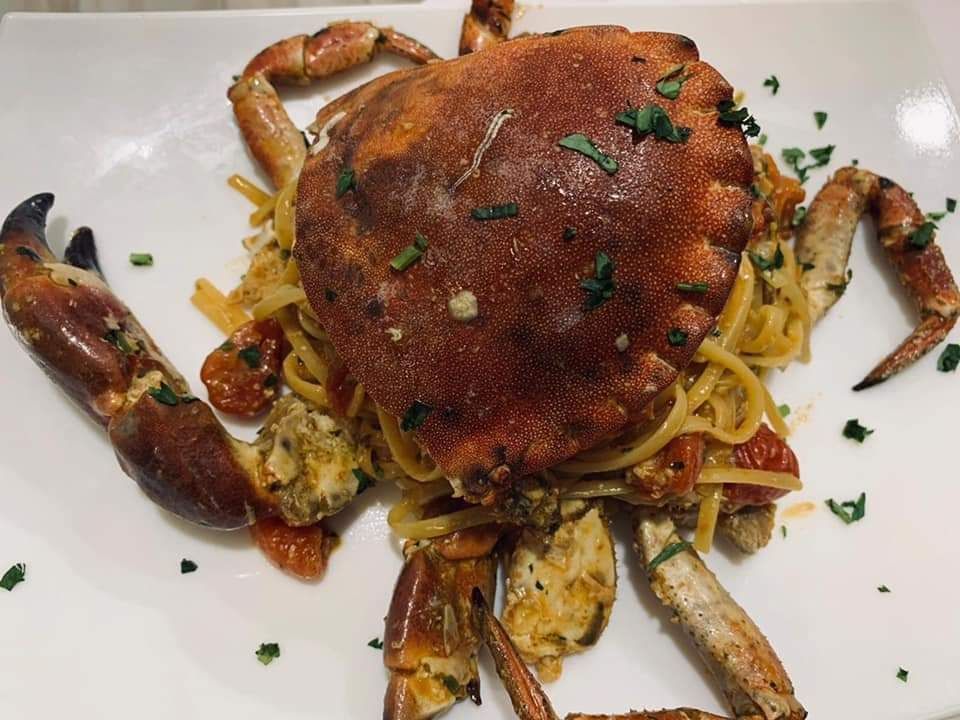 Un piatto bianco con sopra del cibo fritto e una fetta di limone.