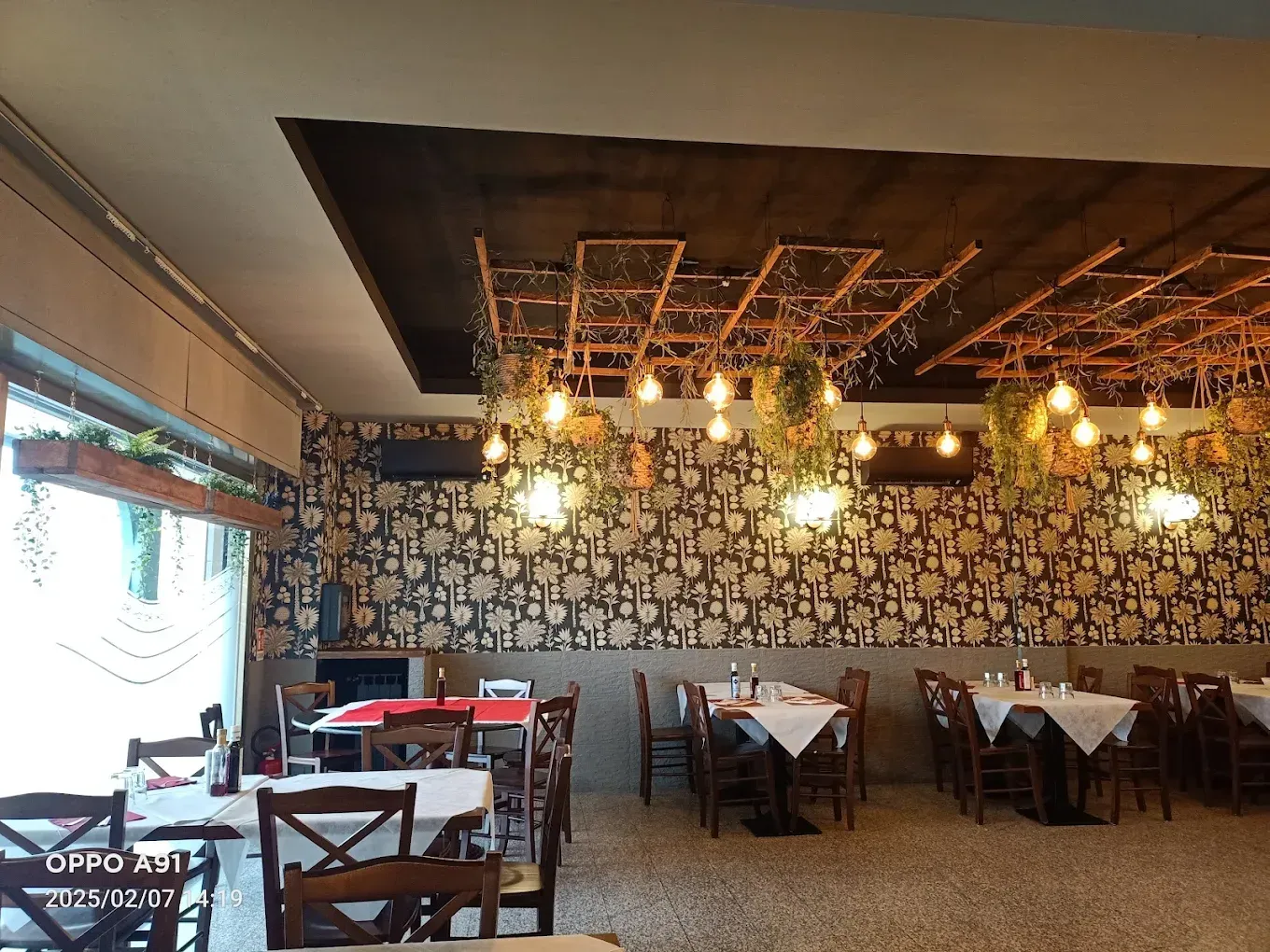 Un ristorante con tavoli e sedie e un soffitto con luci appese.