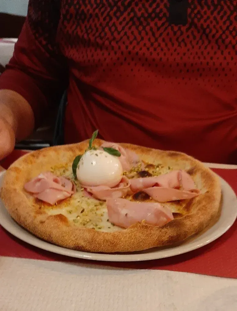 Una pizza con prosciutto e mozzarella su un piatto bianco