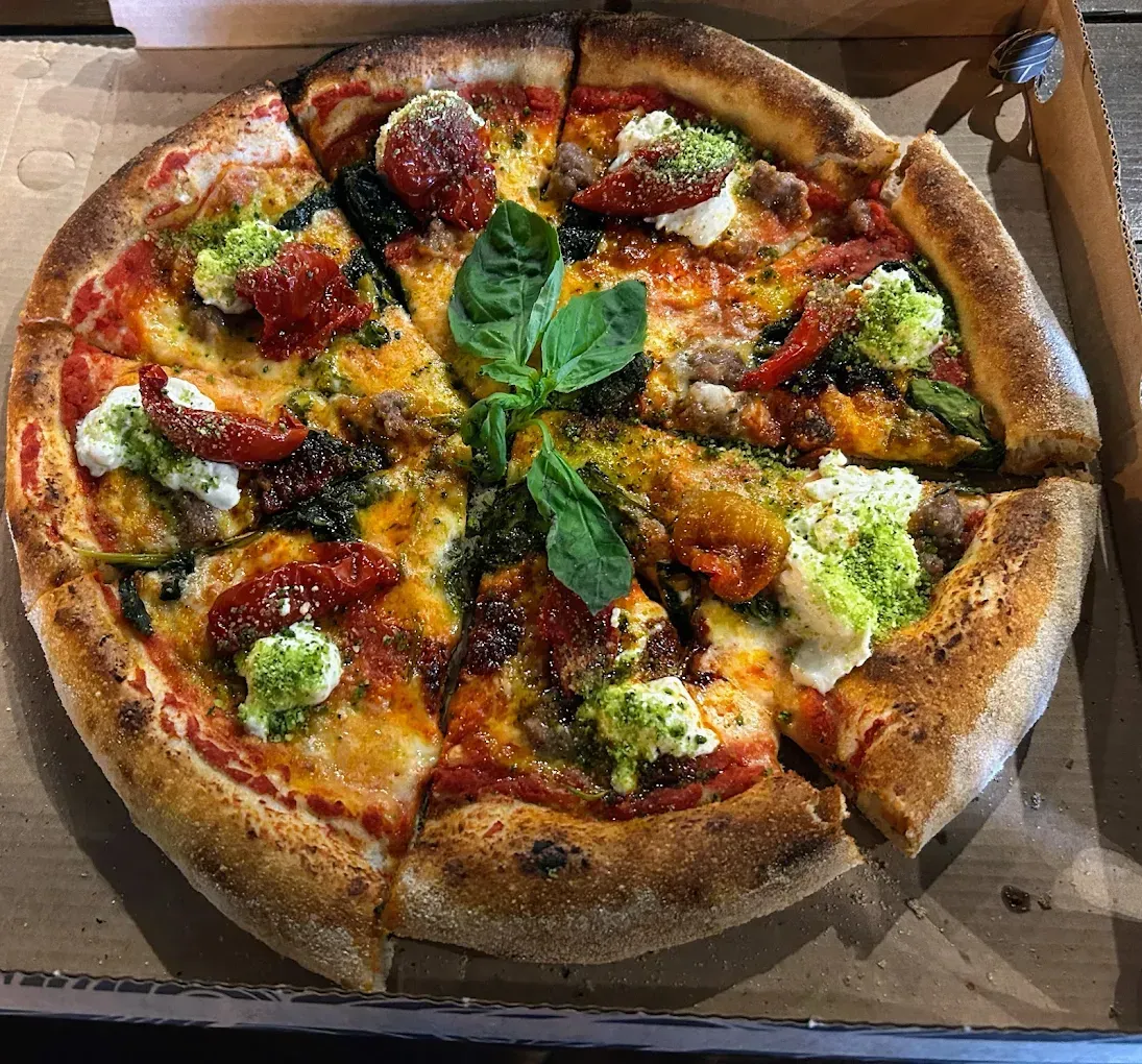 Una pizza con tanti condimenti è in una scatola.
