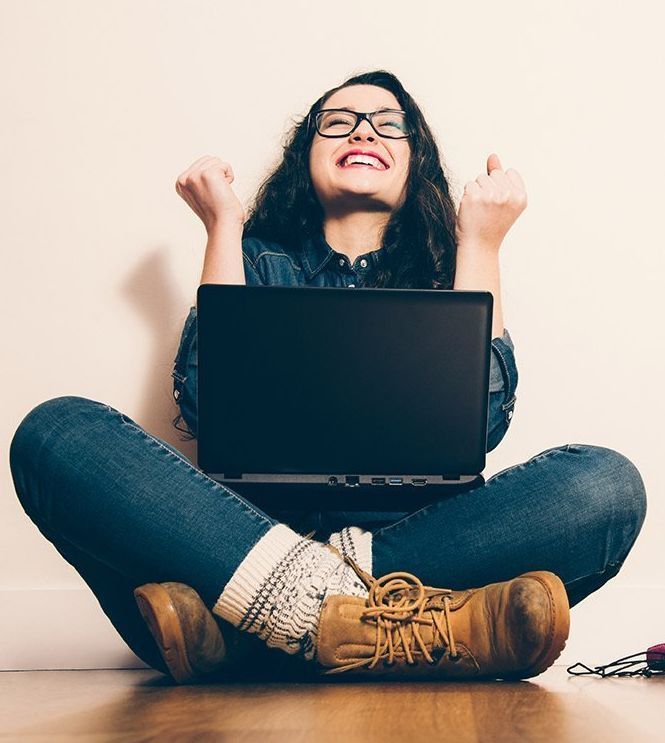 Vrouw met laptop op schoot maakt een juigend gebaar