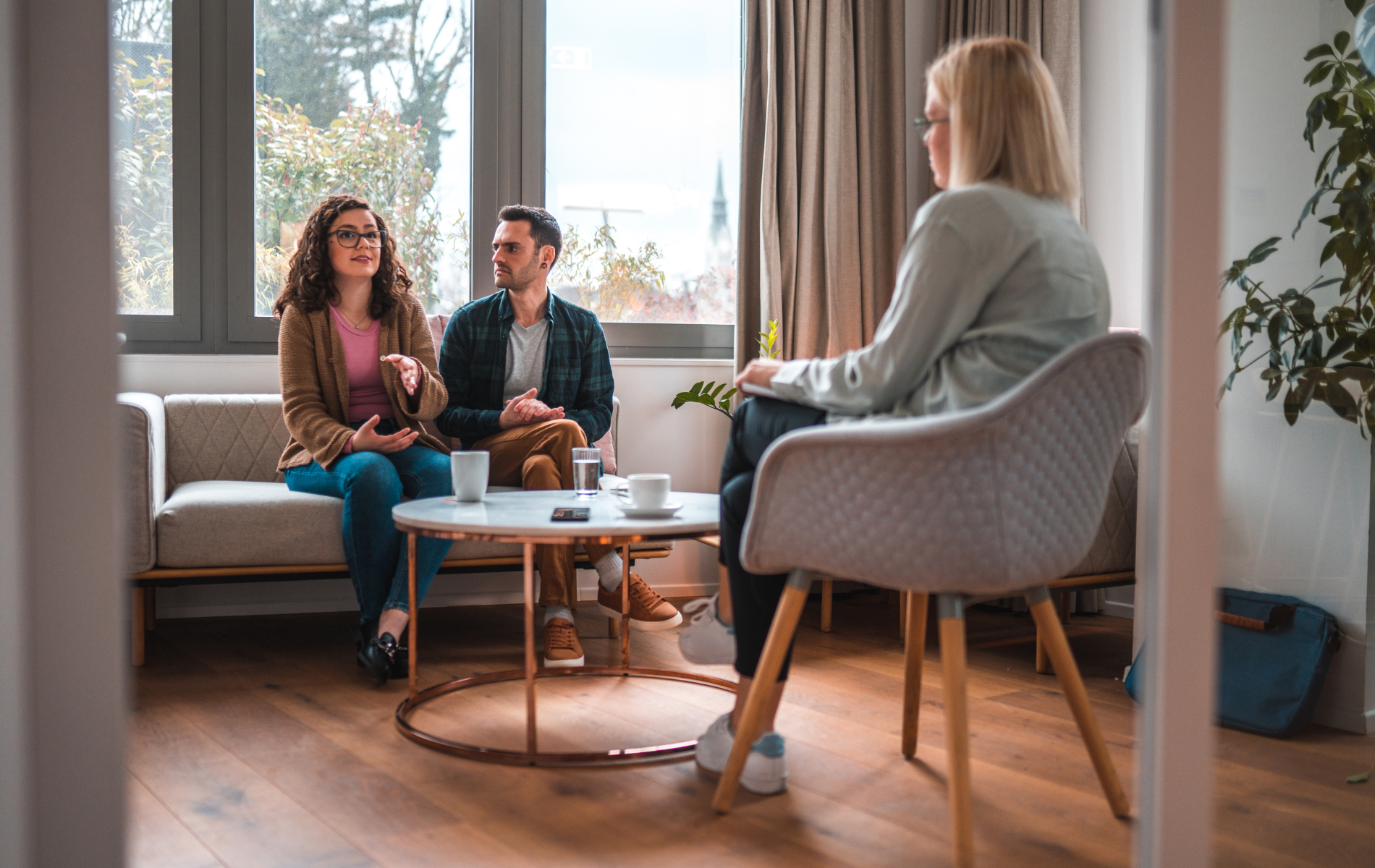 A man and a woman are sitting on a couch talking to a woman.