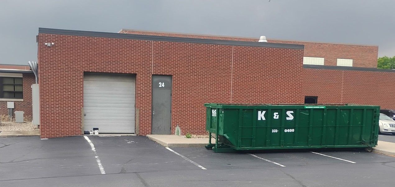 A large green dumpster is parked in front of a store called a center