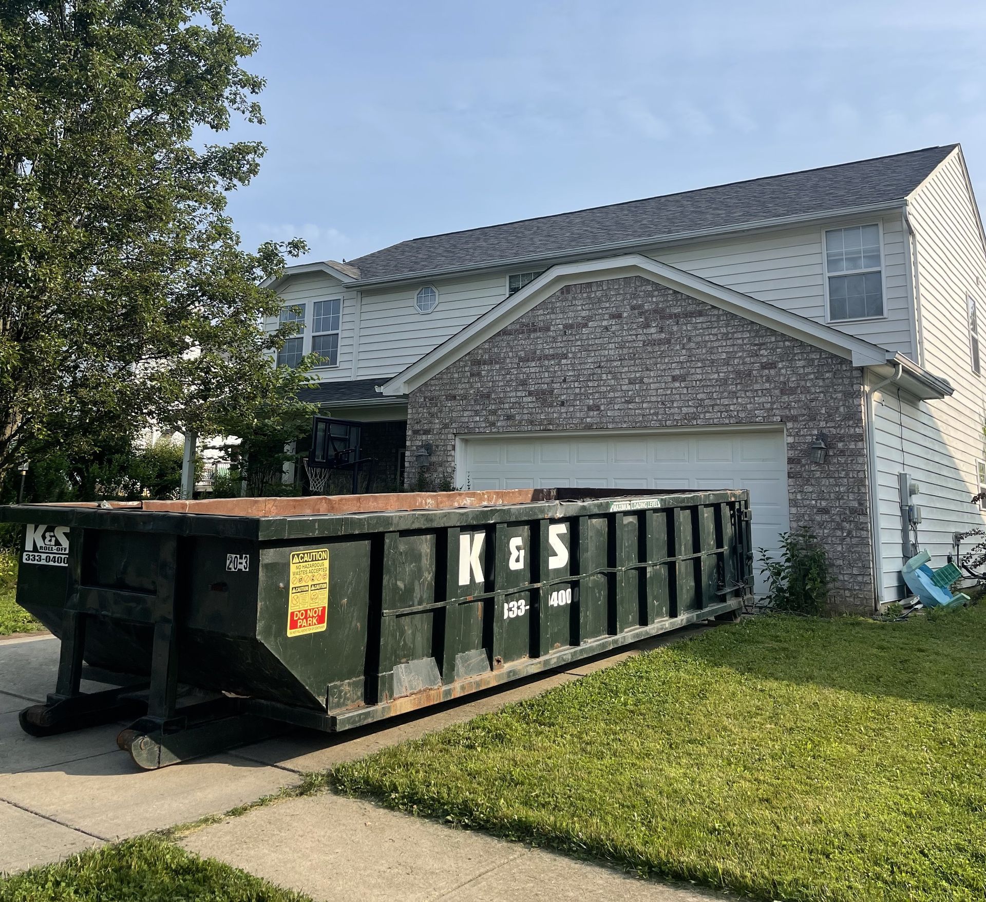 A large green dumpster is parked in front of a store called a center
