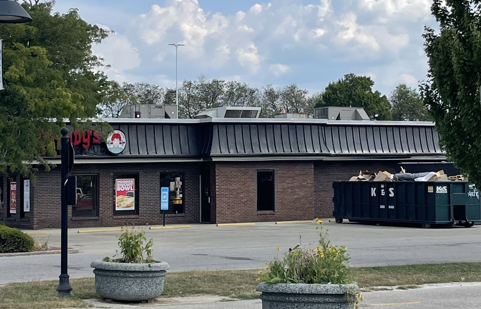 A large green dumpster is parked in front of a store called a center