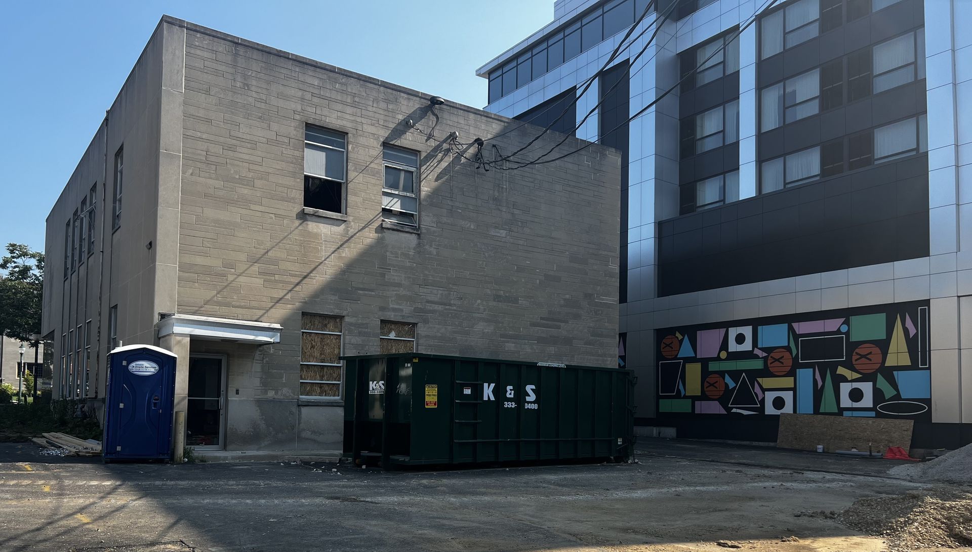 Row of covered garbage bins along a brick wall.