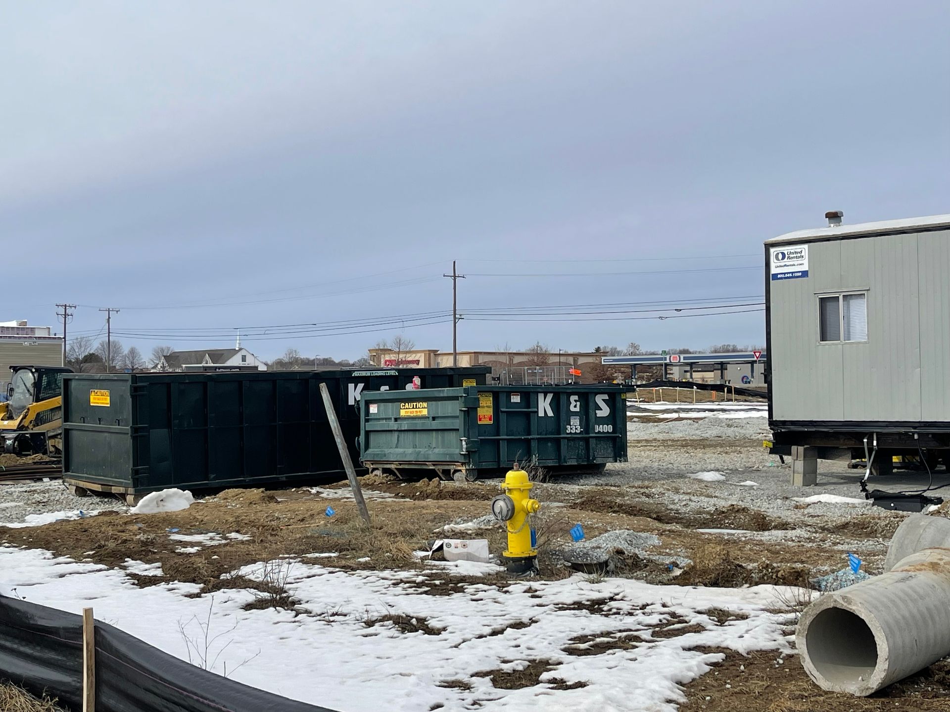 Roll-off dumpster from K & S Rolloff in Trafalgar, IN, being filled with construction debris by an excavator for reliable waste management solutions.