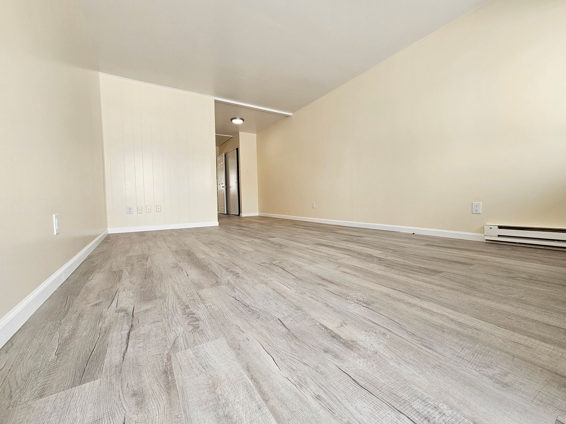 An empty living room with hardwood floors and beige walls.