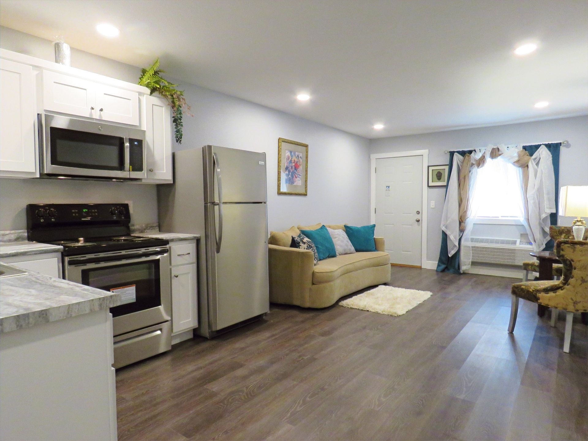 A living room with a couch , refrigerator , stove and microwave.