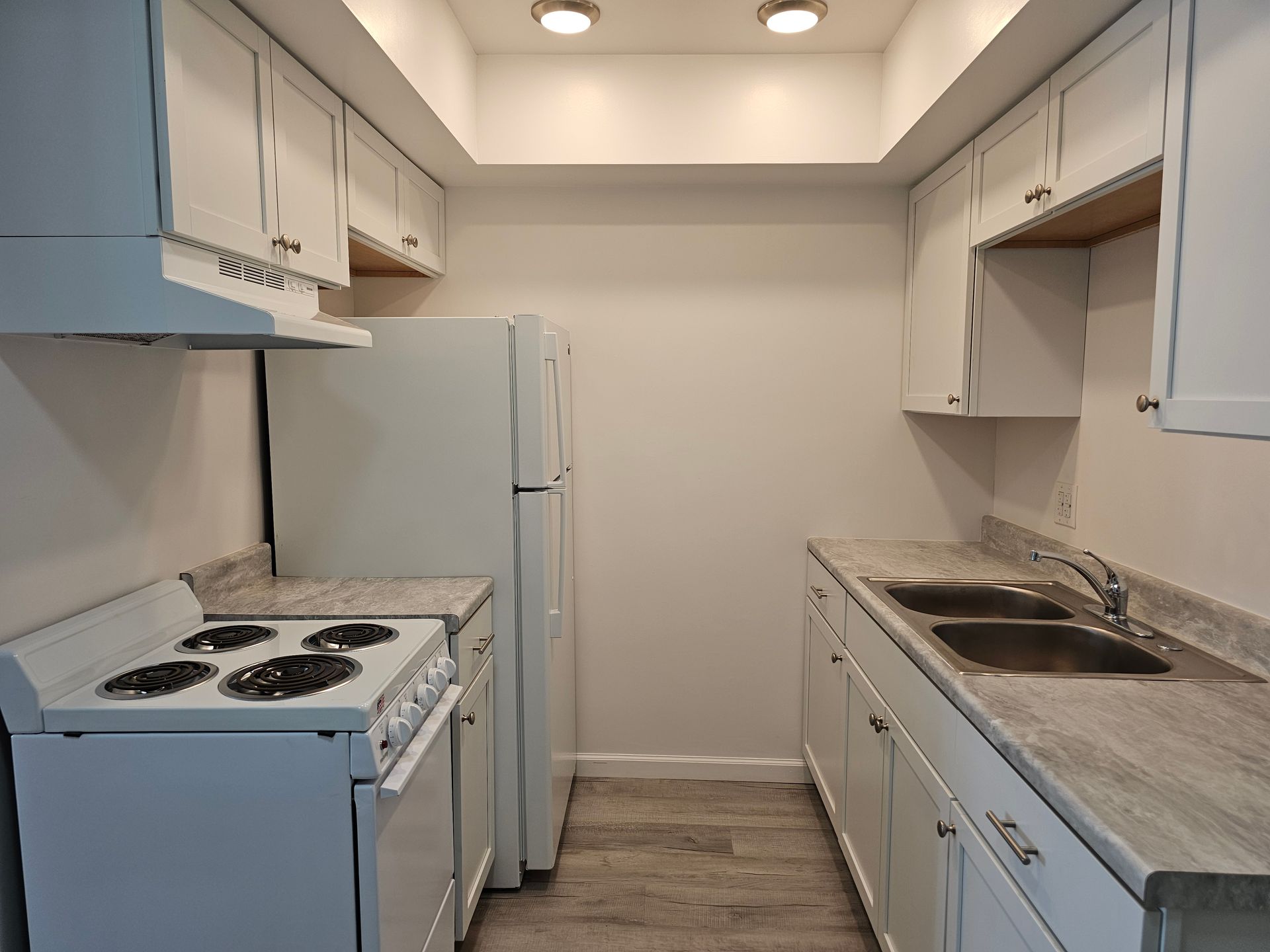 A kitchen with a stove , refrigerator , sink and cabinets