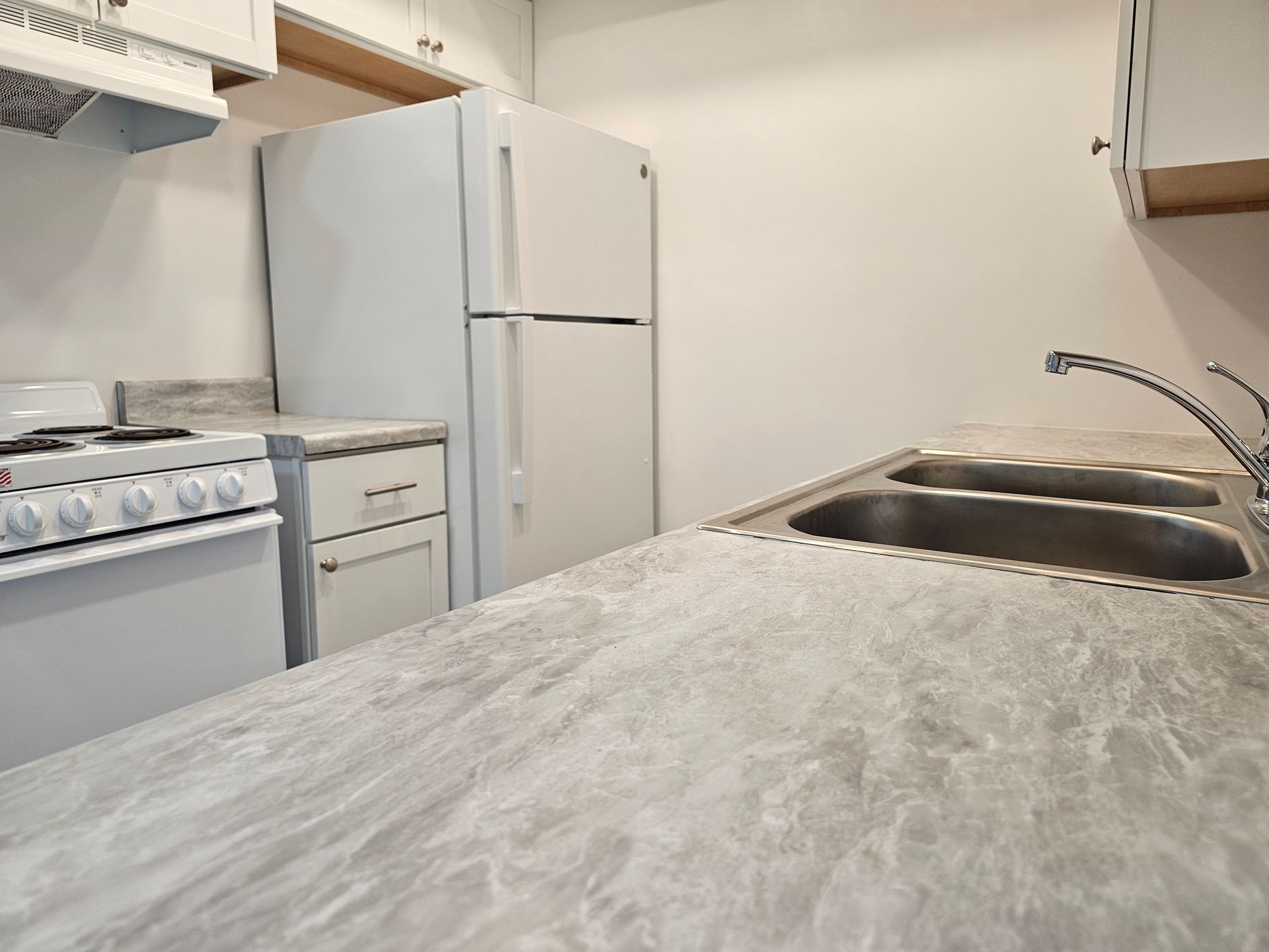 A kitchen with a stove , refrigerator and sink
