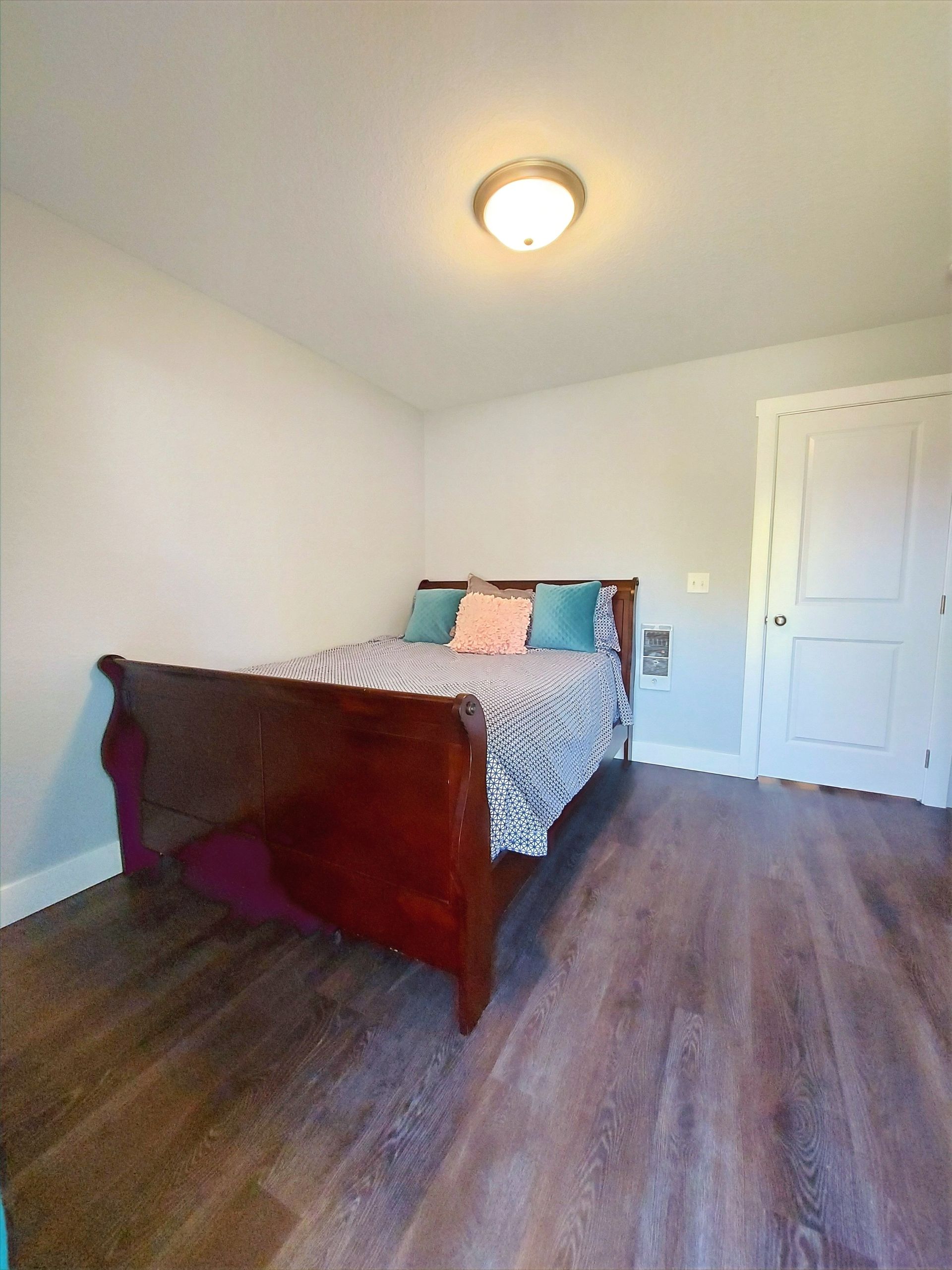 A bedroom with a sleigh bed and hardwood floors.
