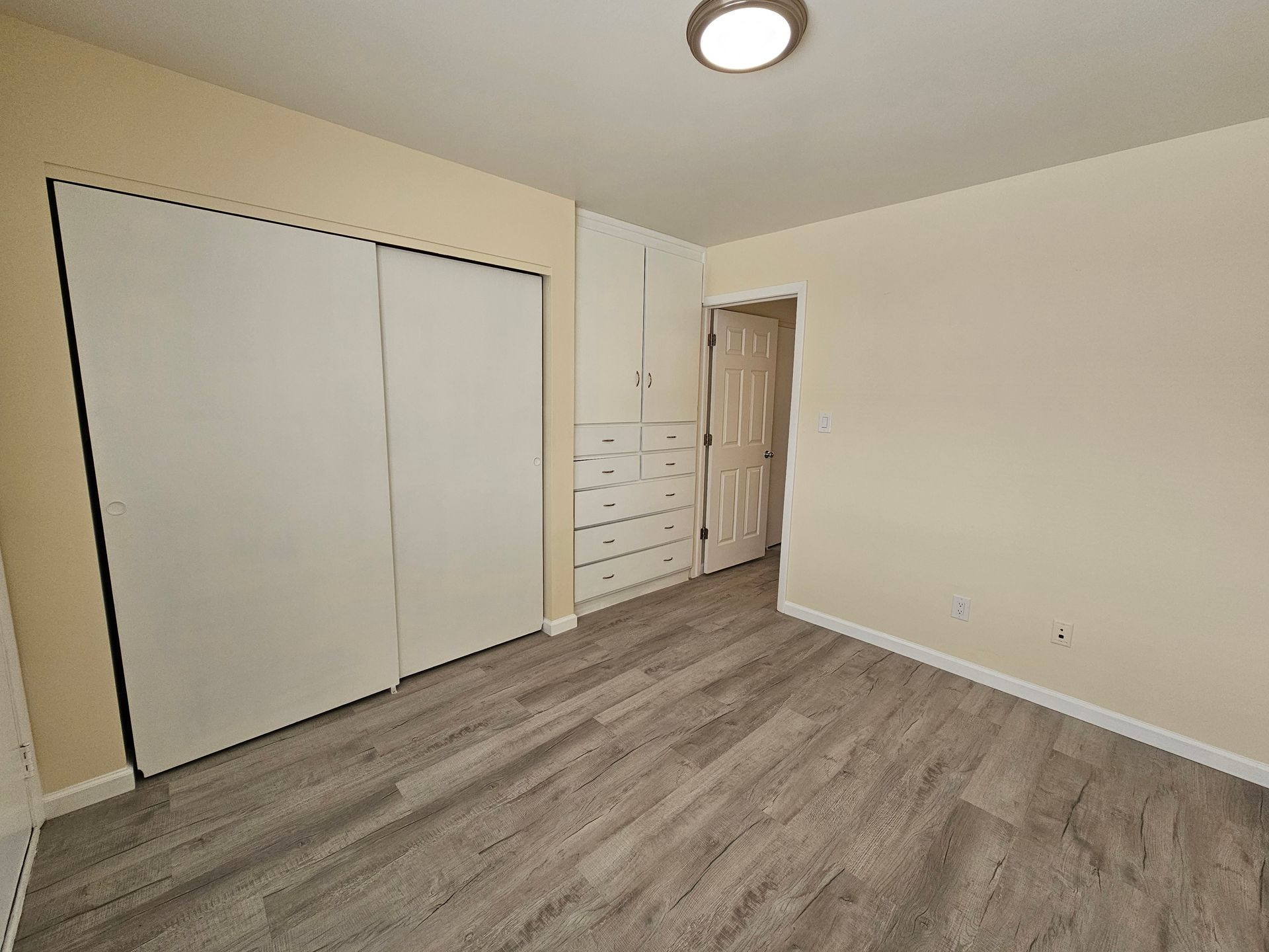 An empty bedroom with hardwood floors and a closet.