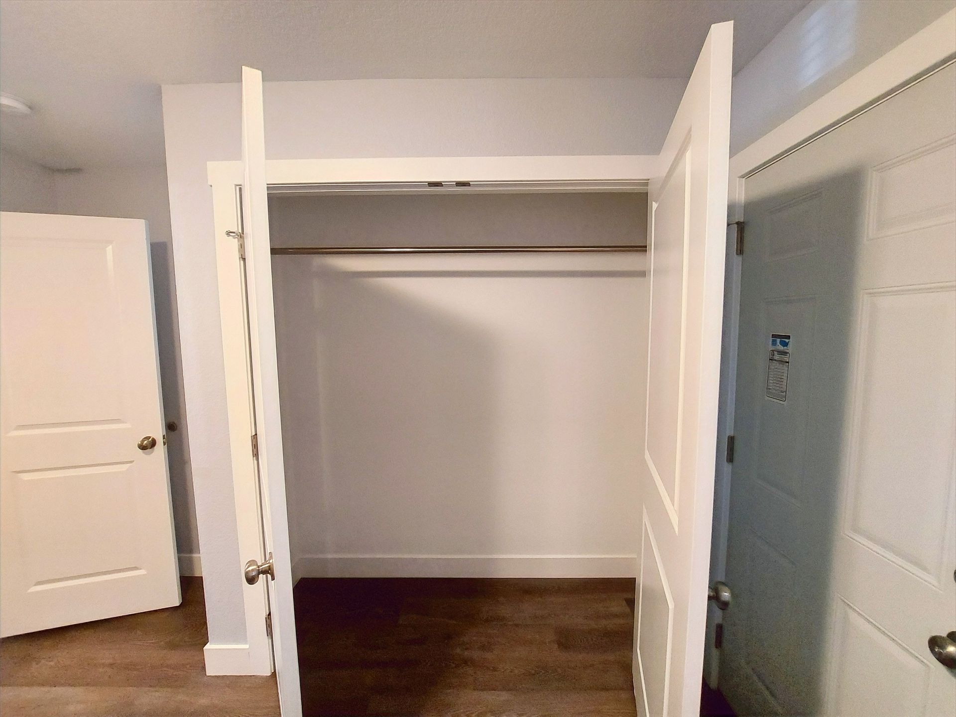 An empty closet with the door open and a hanging rack
