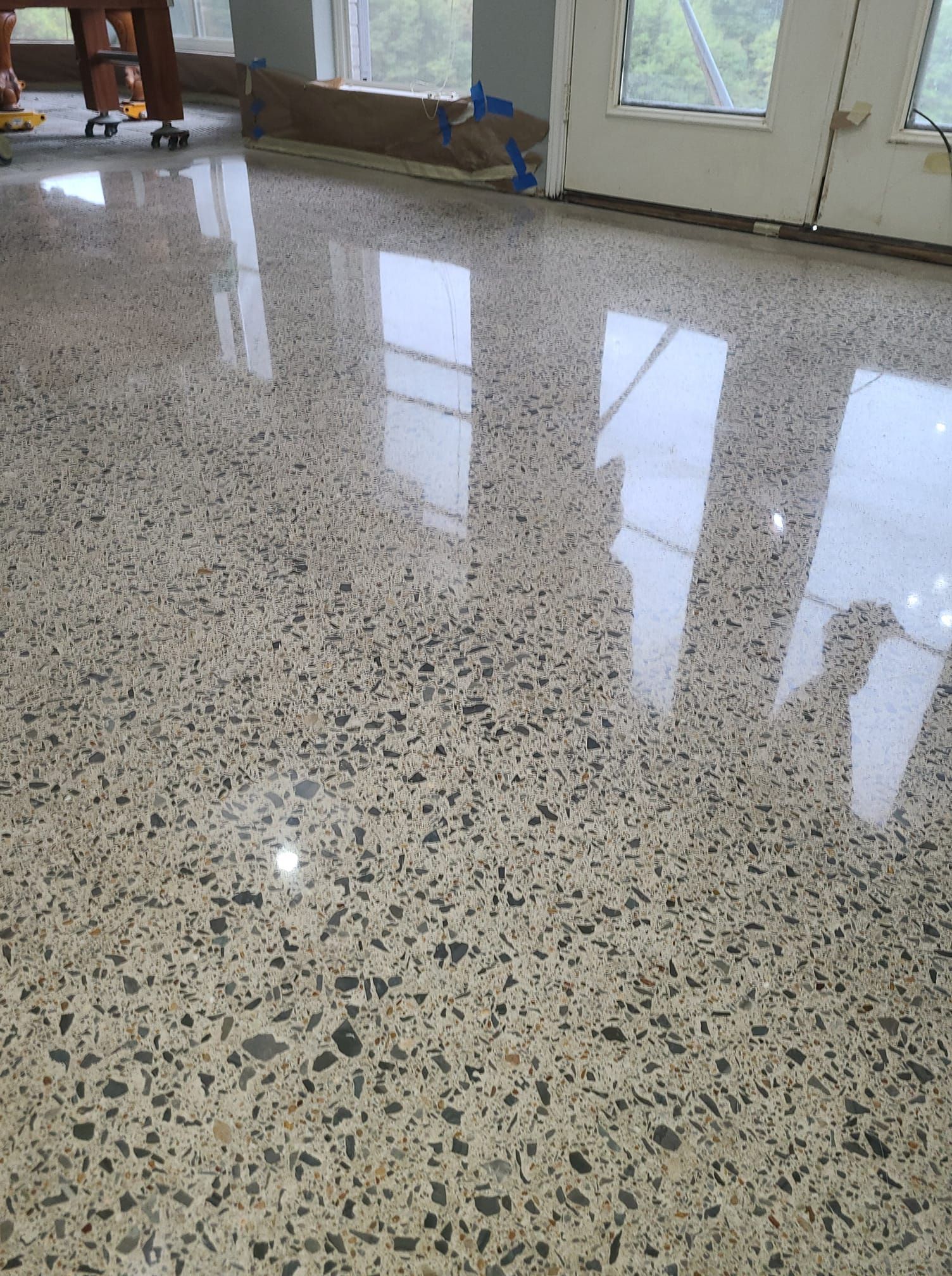 Polished concrete floor with reflections of windows, neutral colors, interior setting.