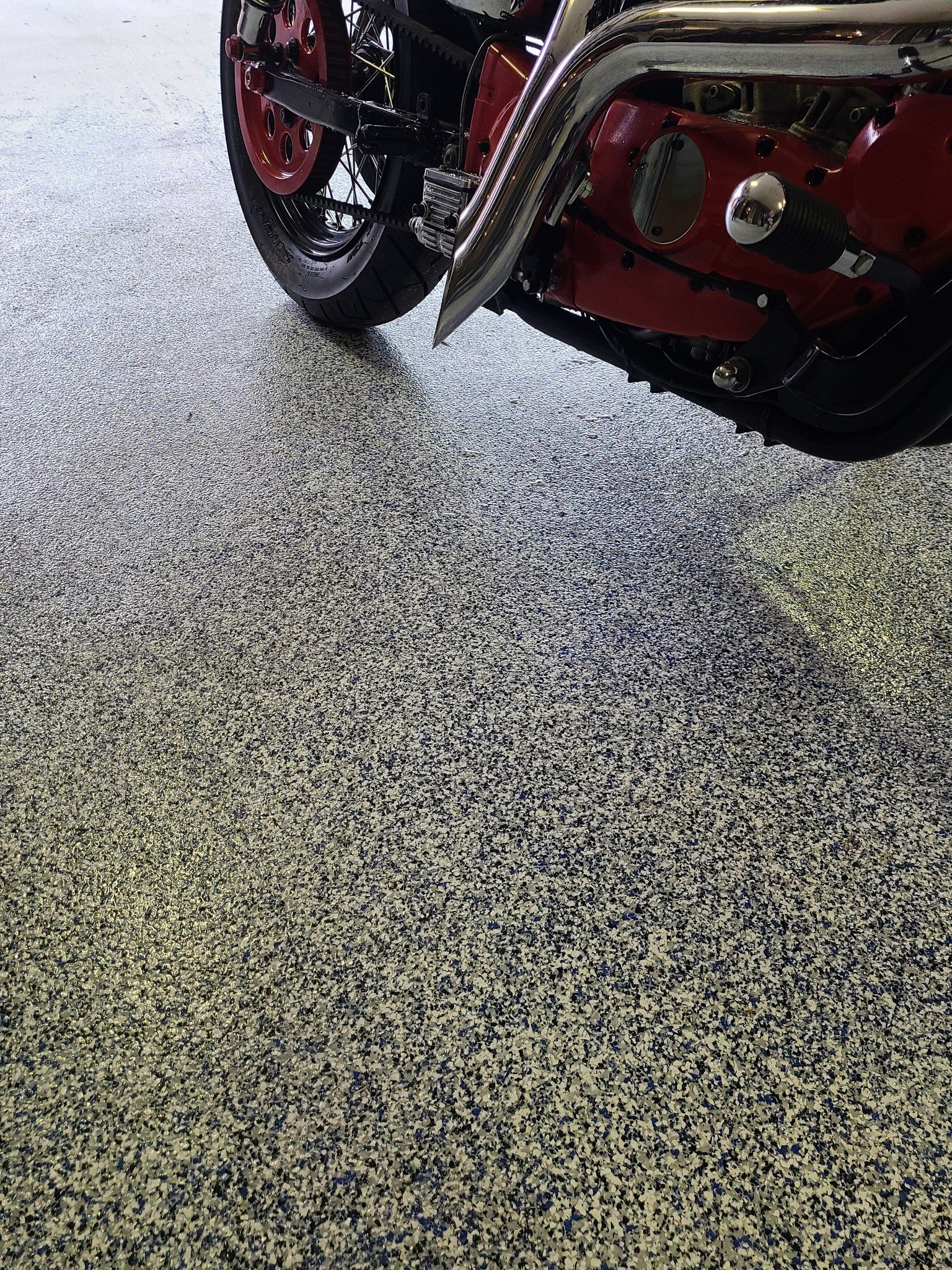 Motorcycle on a speckled gray and black garage floor. Red and black bike details.