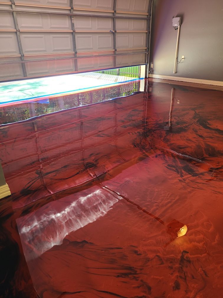 Metallic red epoxy floor with black veining in a garage with the door partially open.