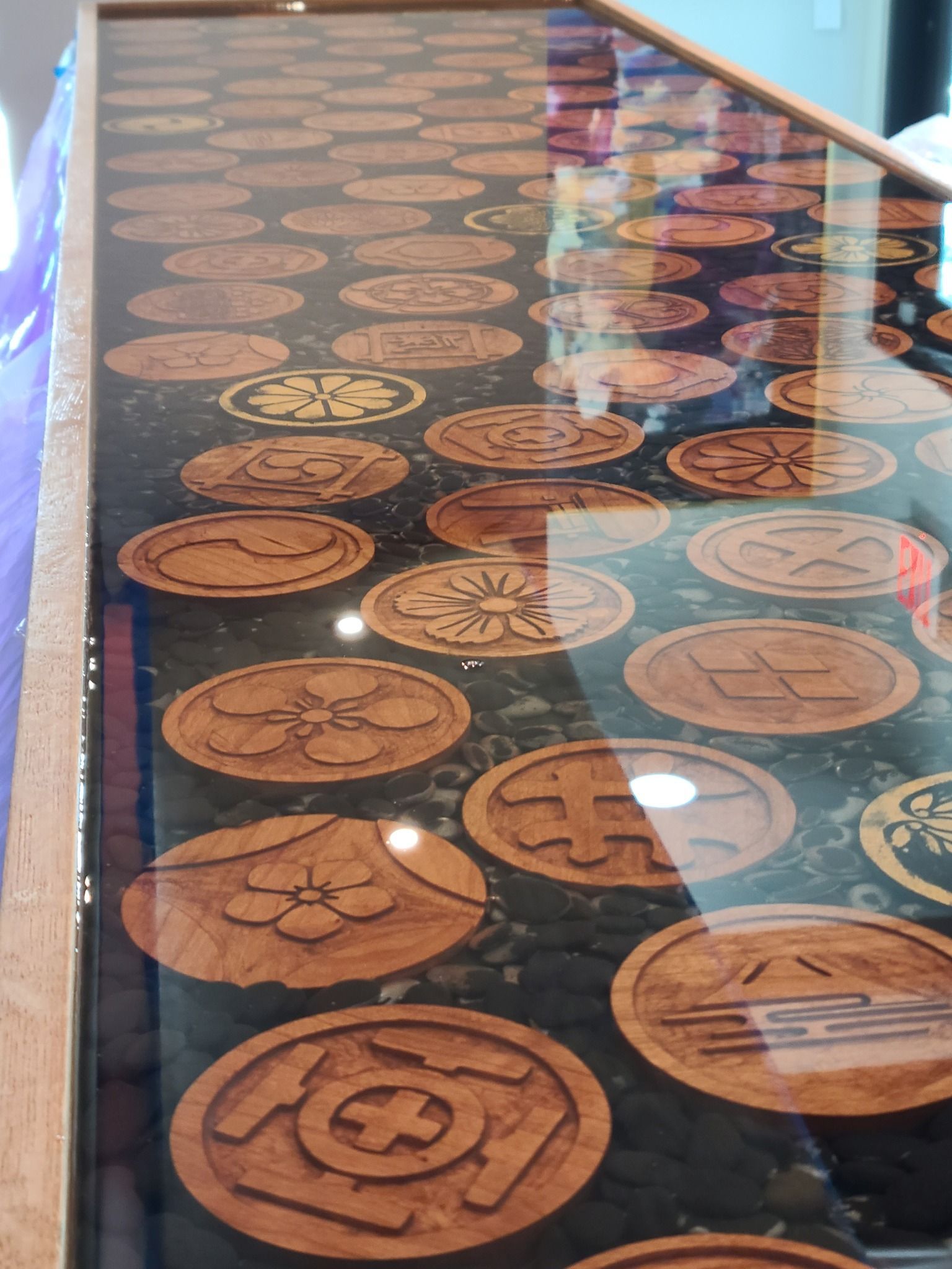 Wooden circular emblems encased in resin, embedded in dark surface. Close-up.