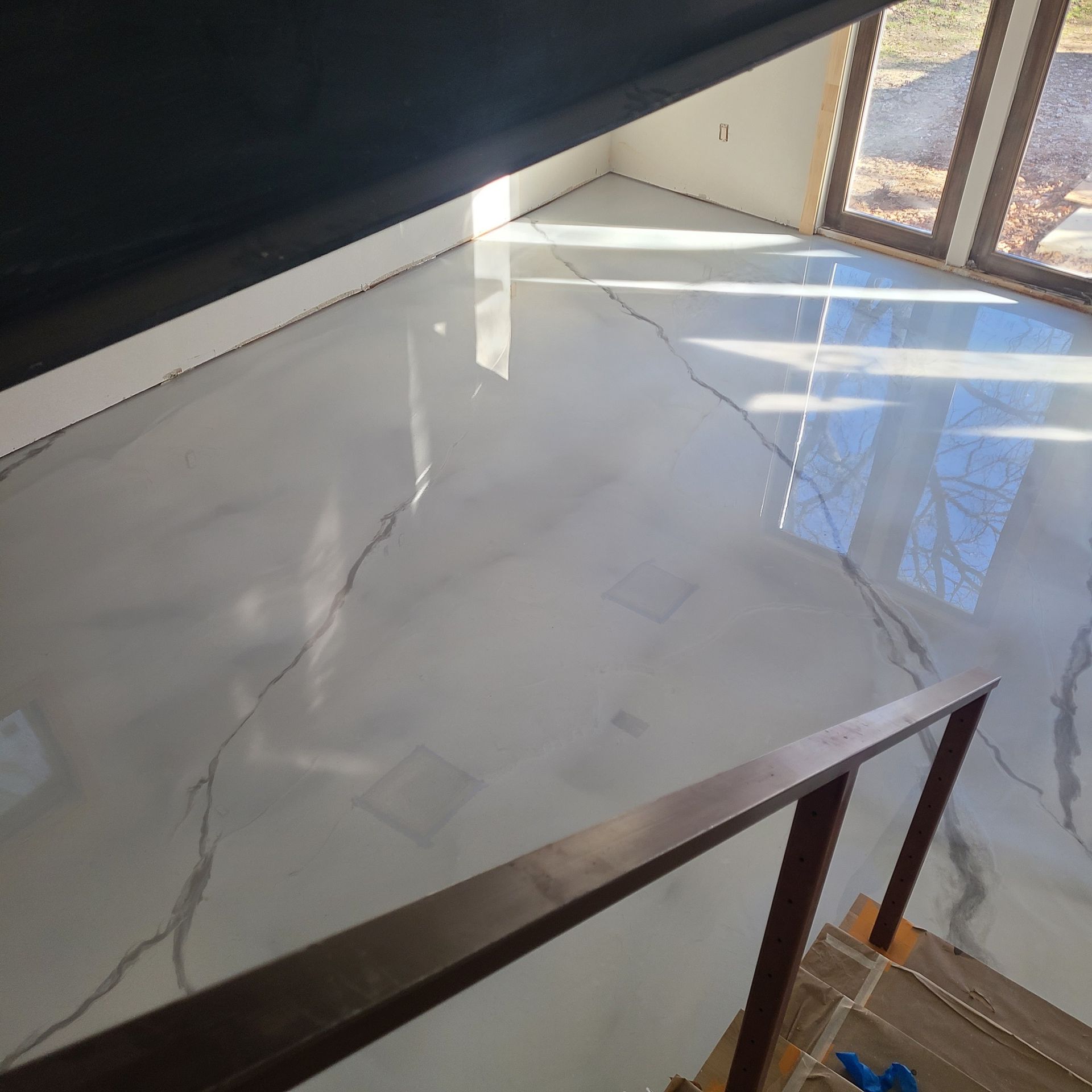 Glossy, marbled white and gray epoxy floor in a room with dark trim and windows.
