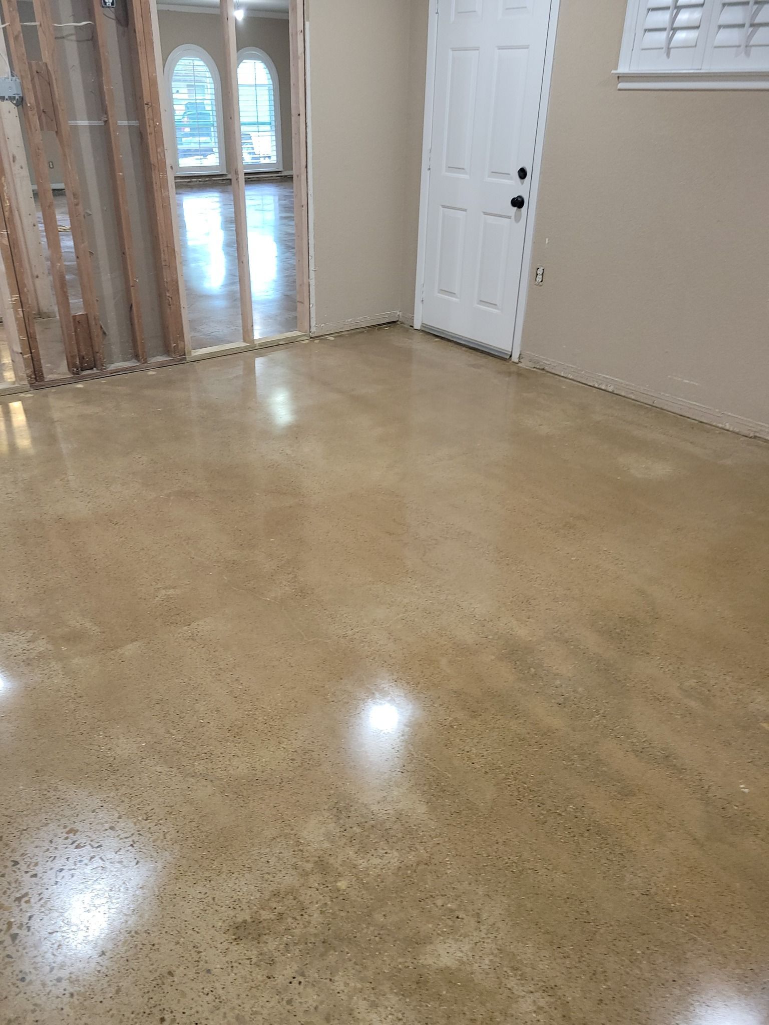 Polished concrete floor in a room with a white door and beige walls.