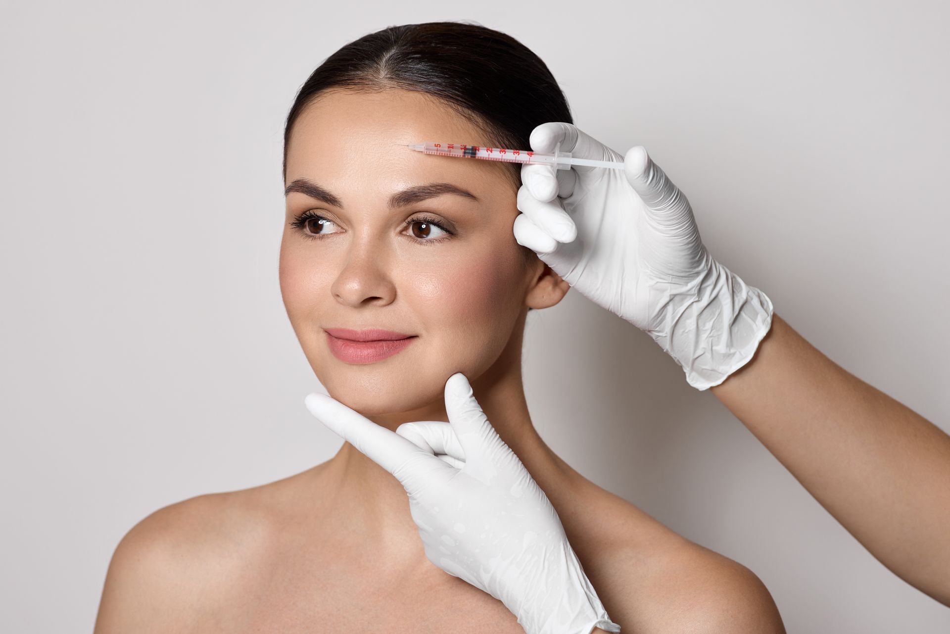 Botulinum toxin injections near a woman's forehead for blocking mimic wrinkles and wrinkles removal.
