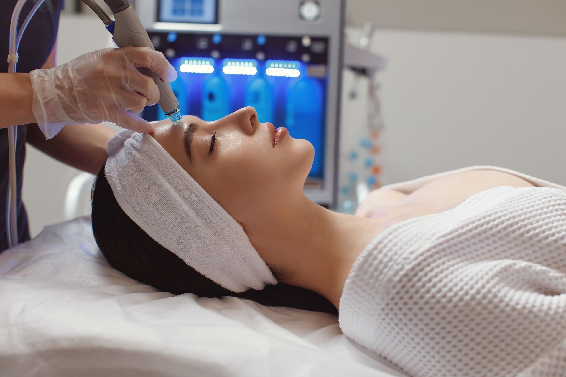 A woman is getting microdermabrasion therapy on the forehead.