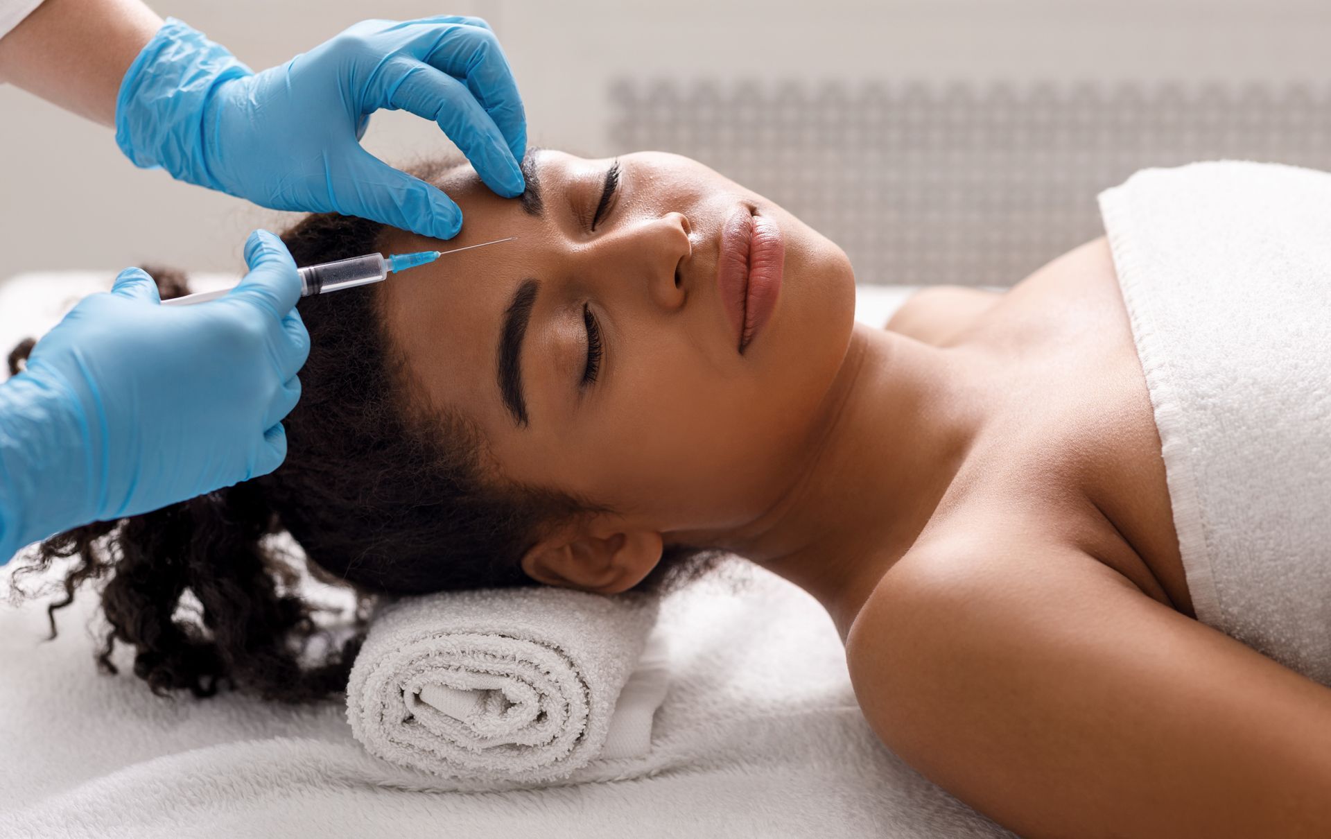 Black woman getting beauty injection at spa.